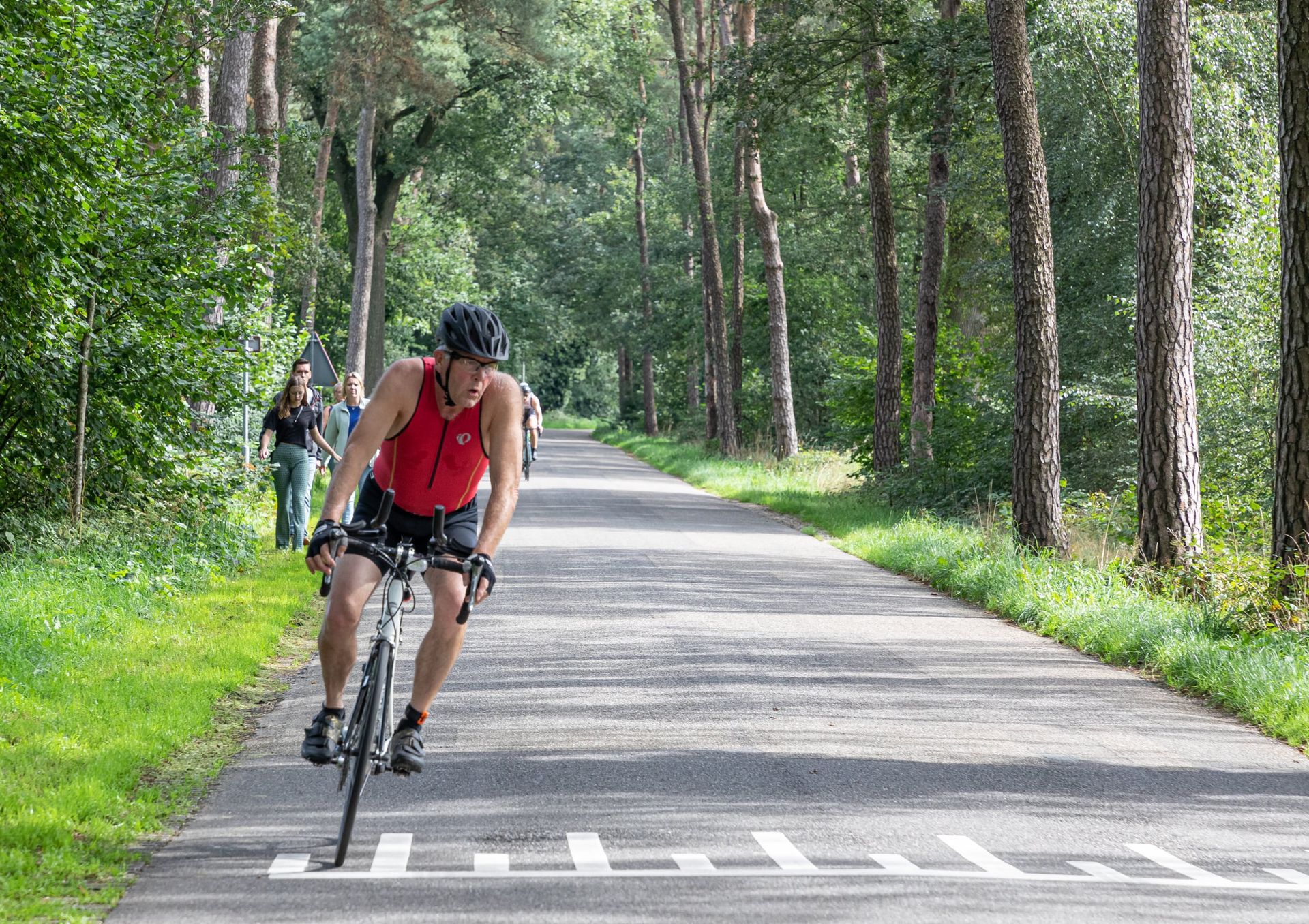Een man fietst over een weg in het bos.