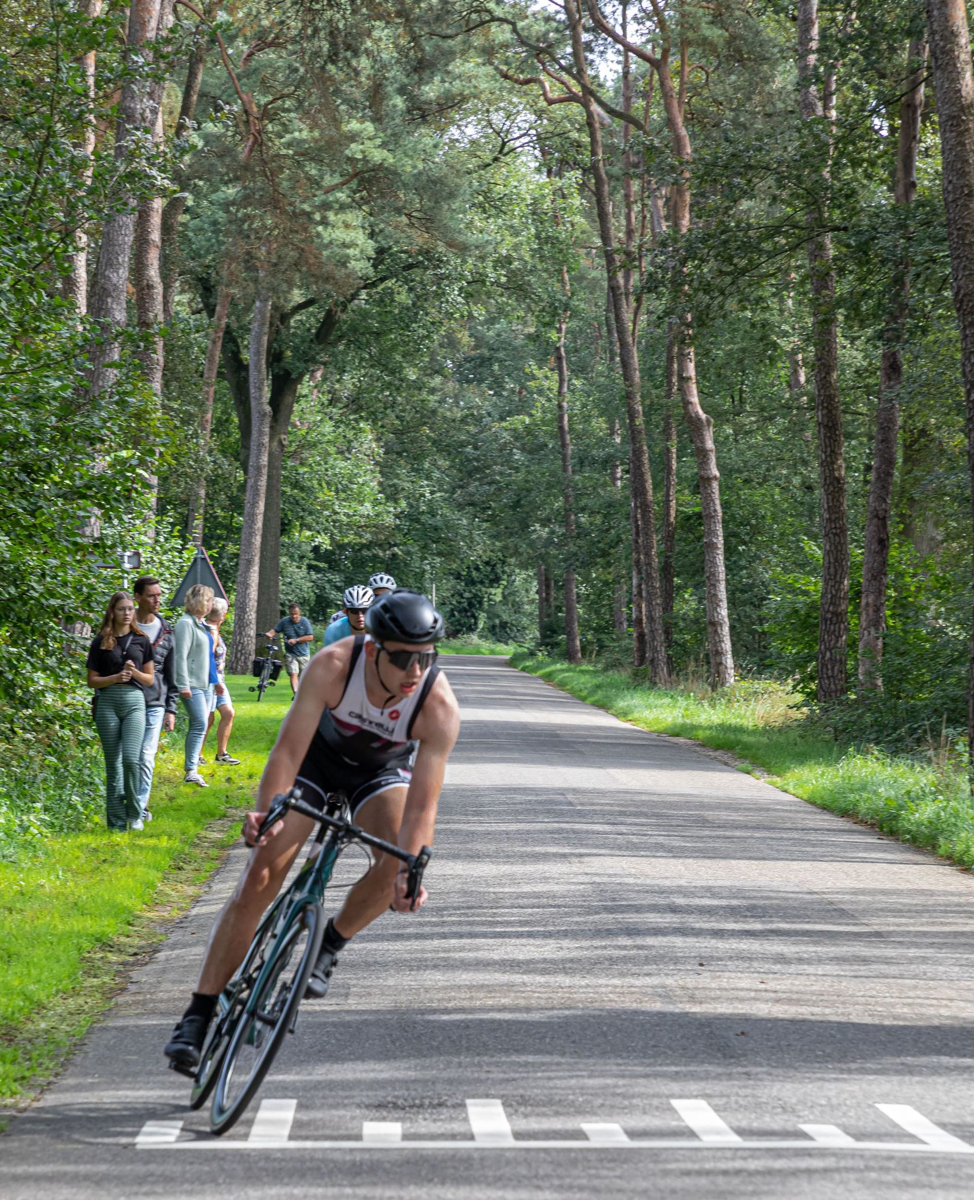 Een man fietst over een weg in het bos.
