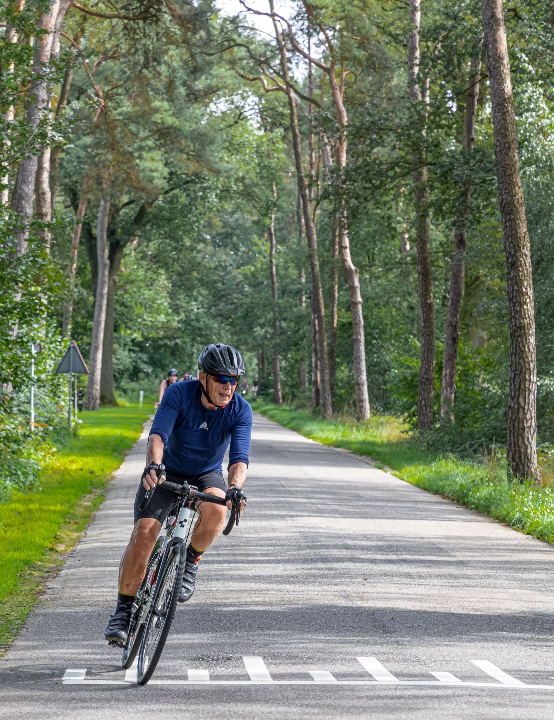 Een man fietst over een weg in het bos.