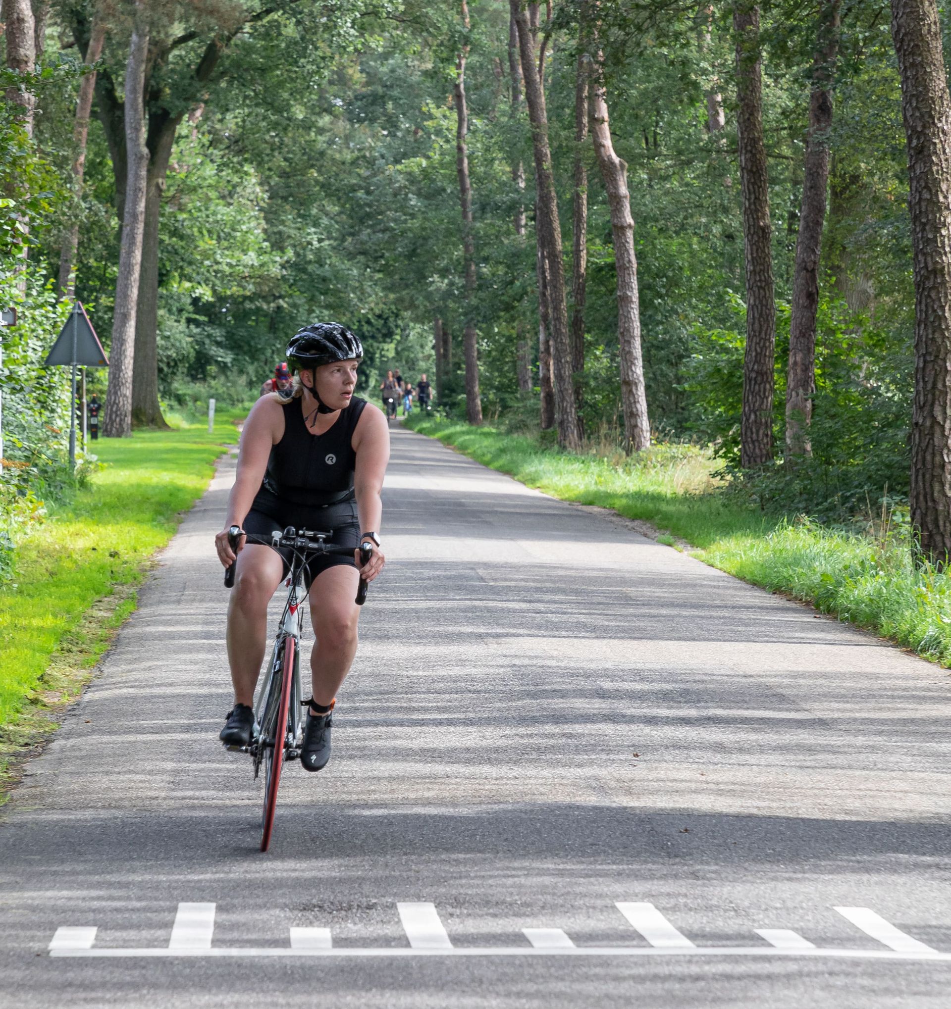 Een man met een helm rijdt op een fiets over een weg