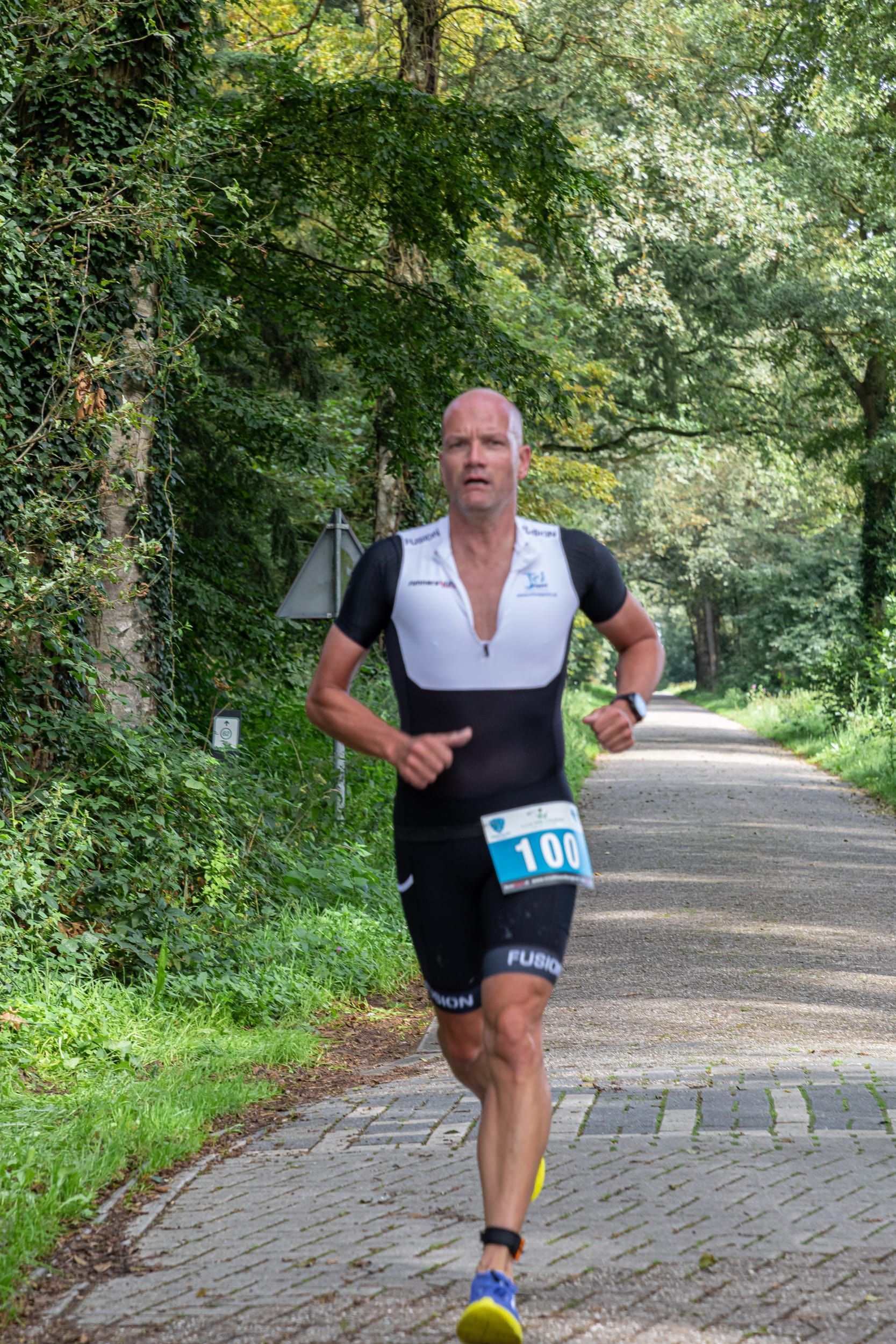 Een man rent over een stenen weg in het bos.