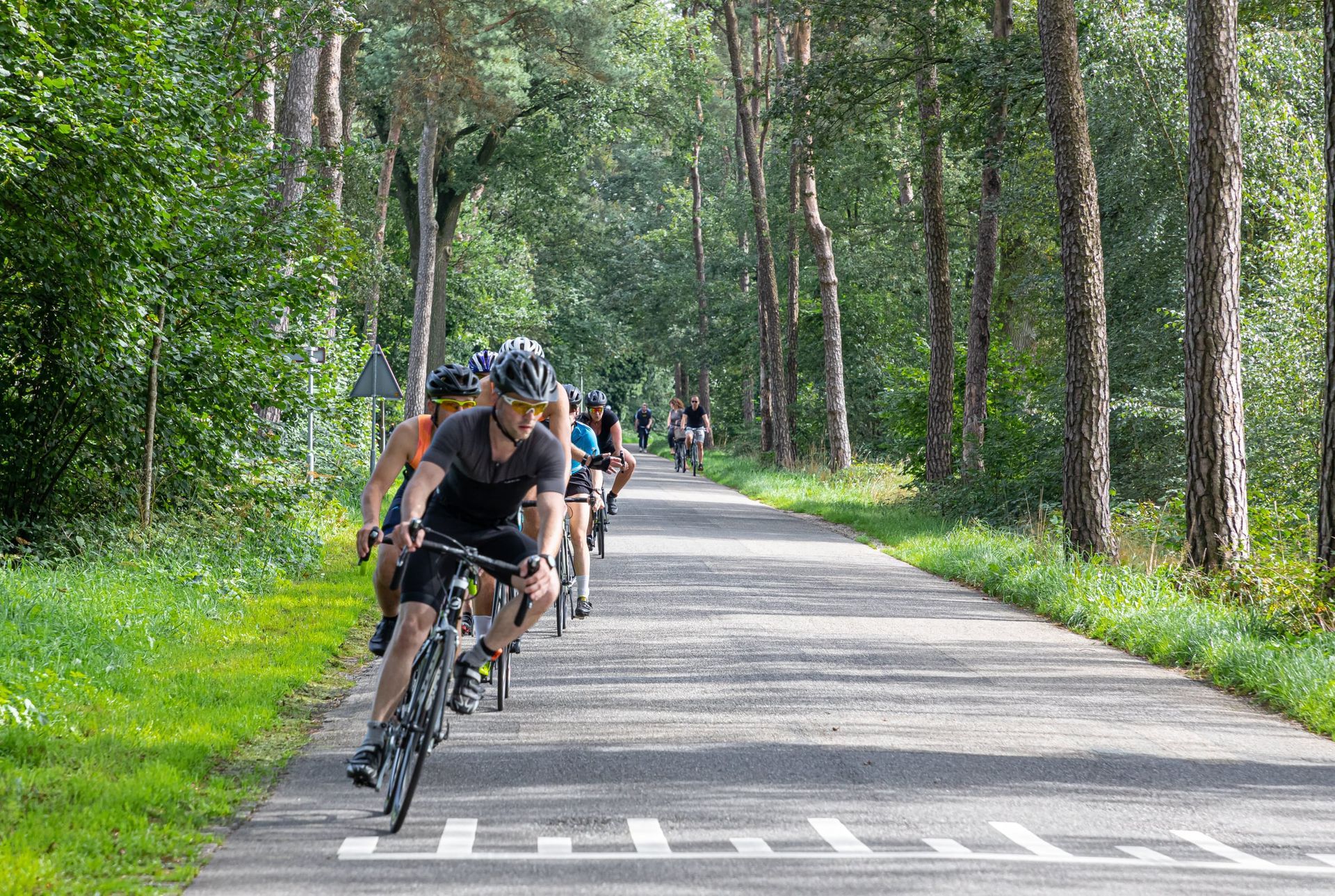 Een groep mensen fietst over een weg.