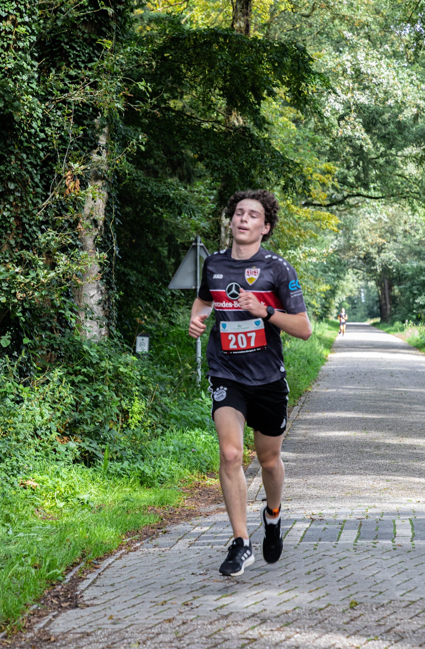 Een jongeman rent over een pad in het bos.