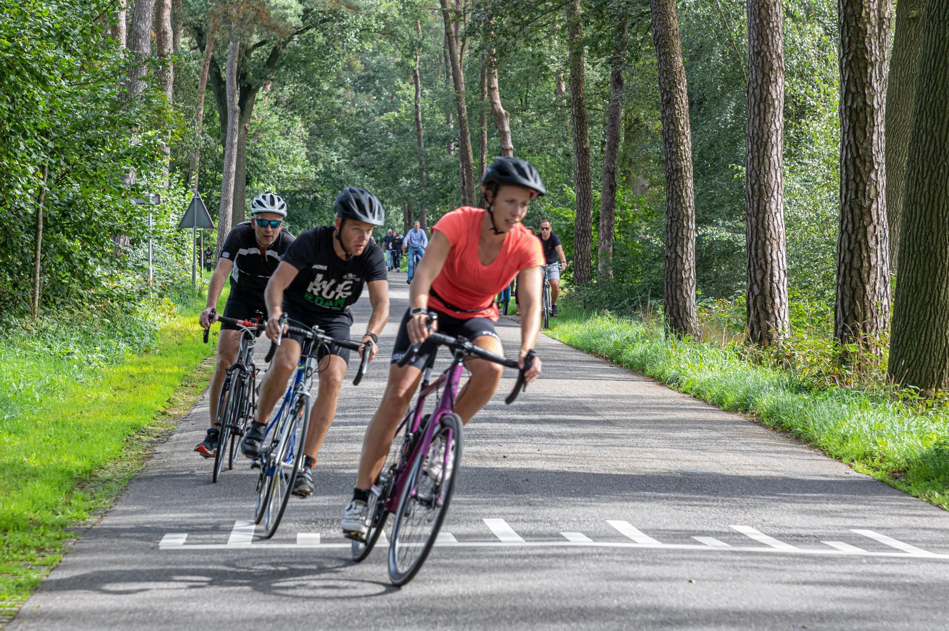 Een groep mensen fietst over een weg.
