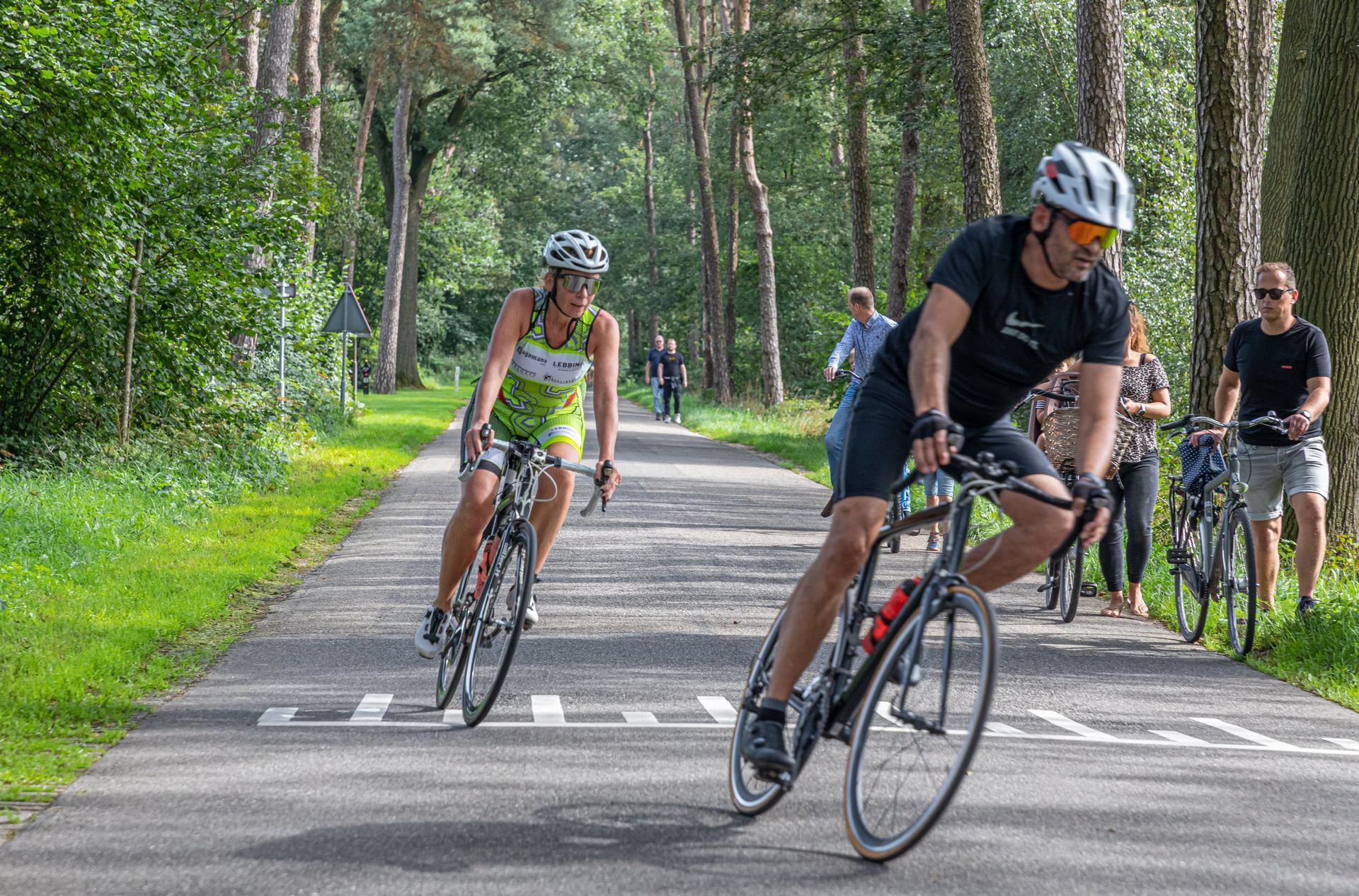 Een man en een vrouw fietsen over een weg.