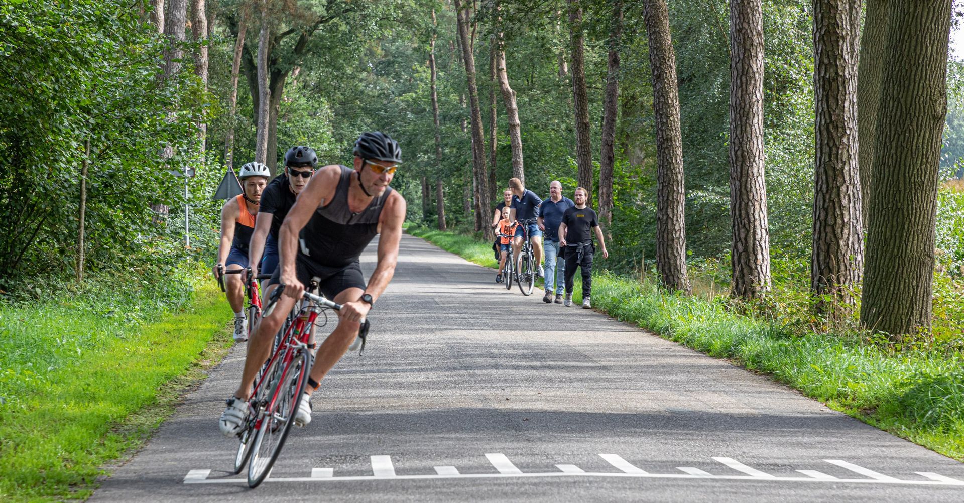 Een groep mensen fietst over een weg.