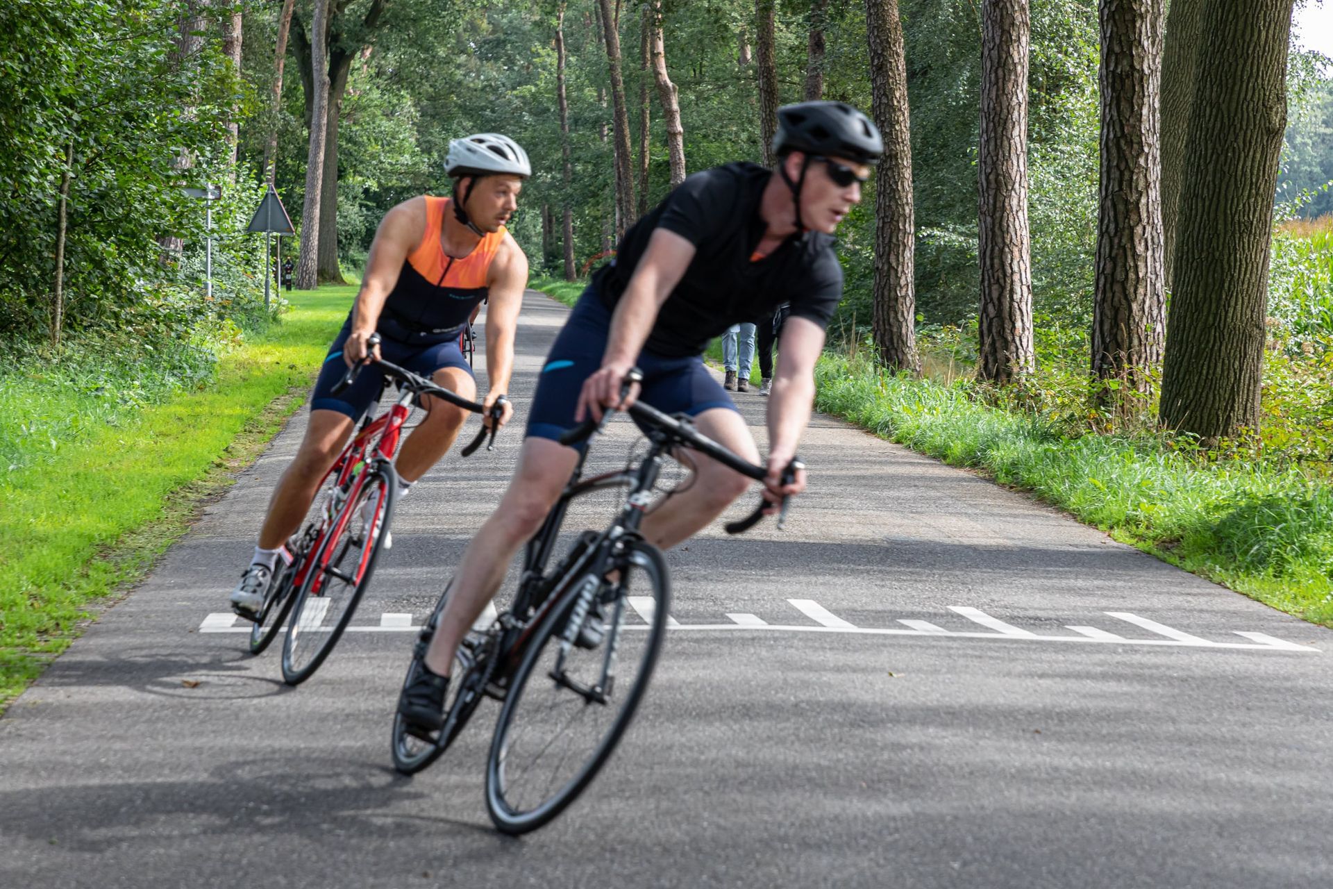 Een man en een vrouw fietsen over een weg.