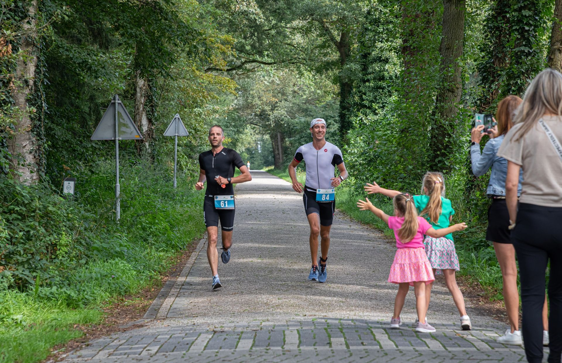 Een groep mensen rent over een stenen weg.
