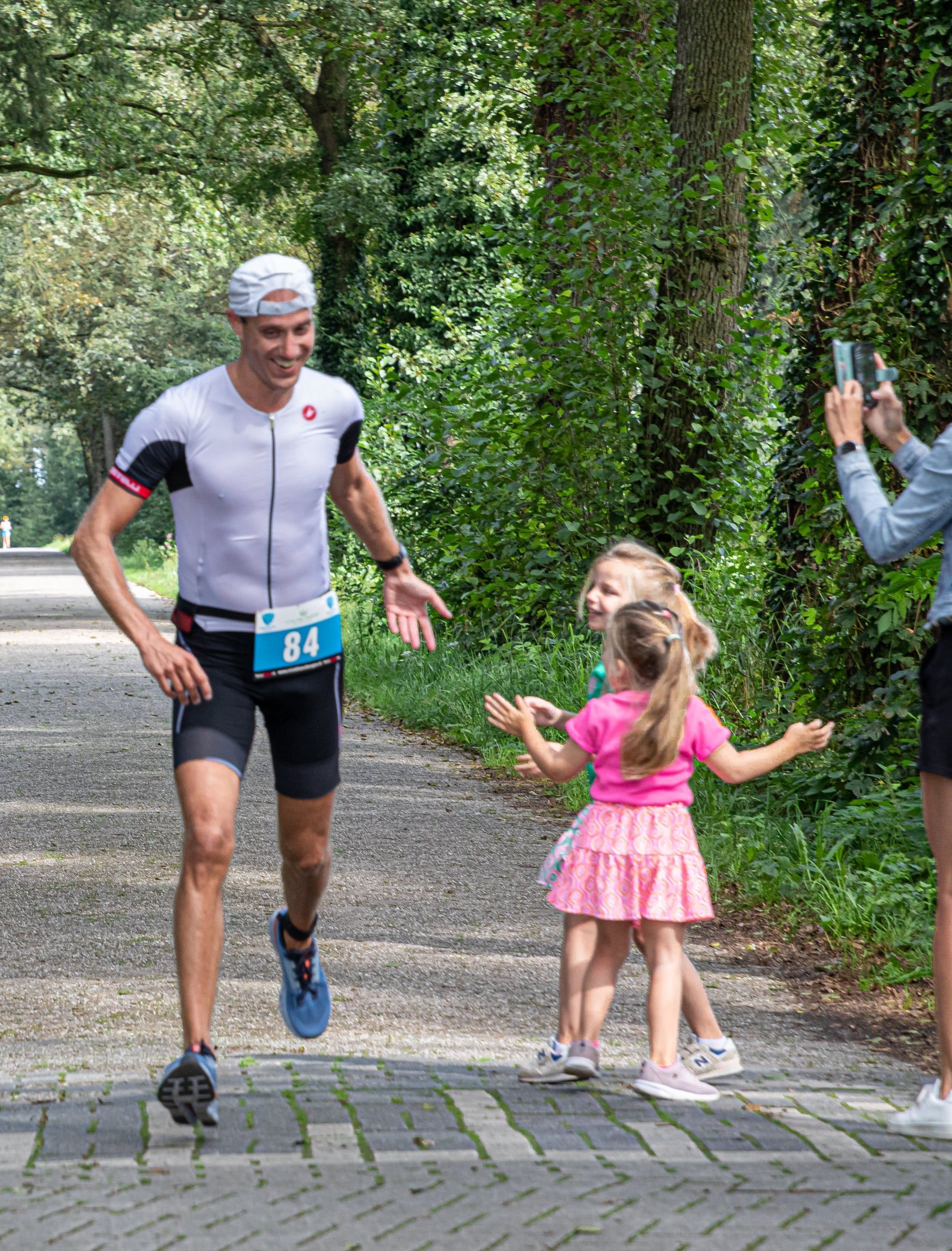 Een man rent met twee kleine meisjes over een pad.
