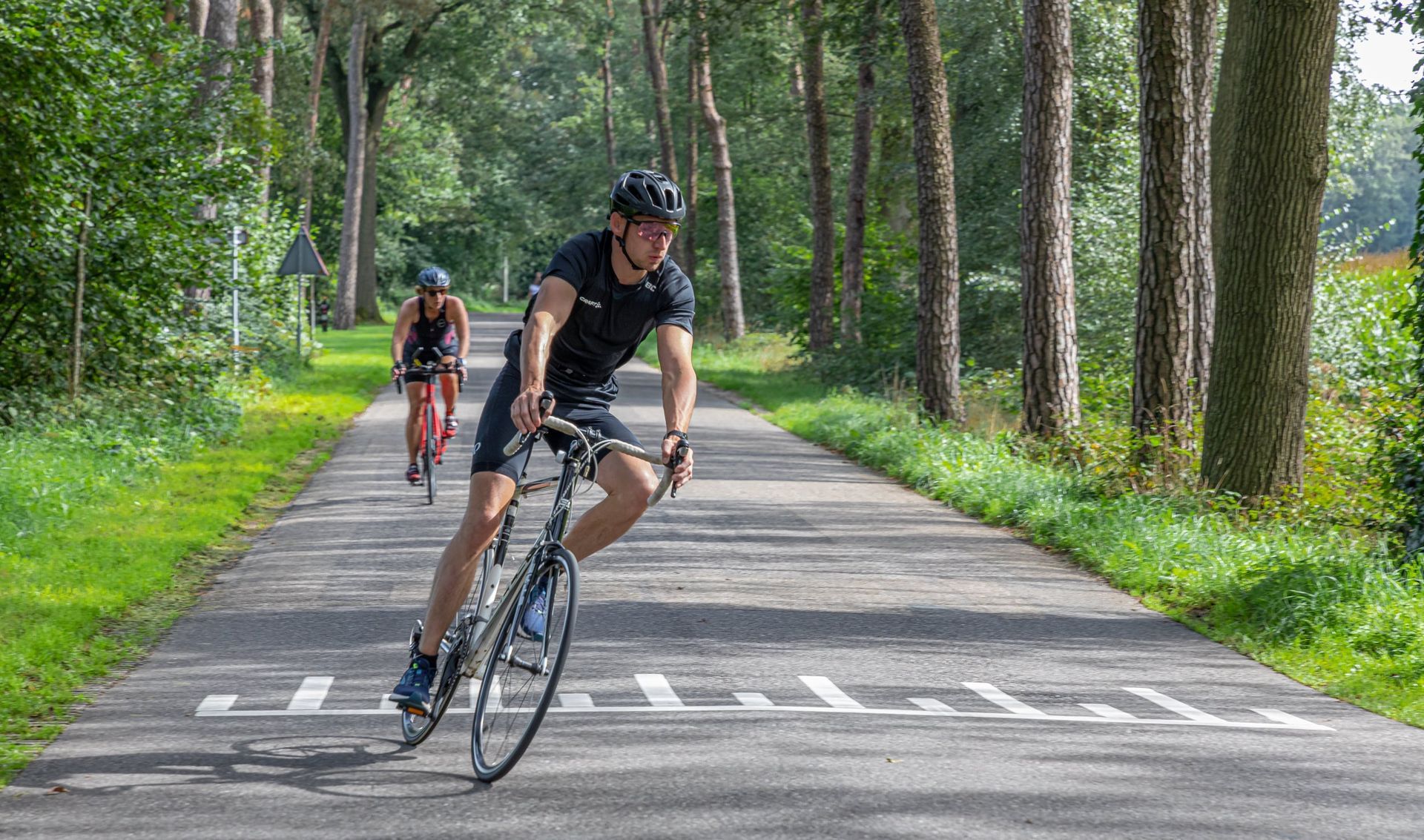 Een man fietst over een weg in het bos.