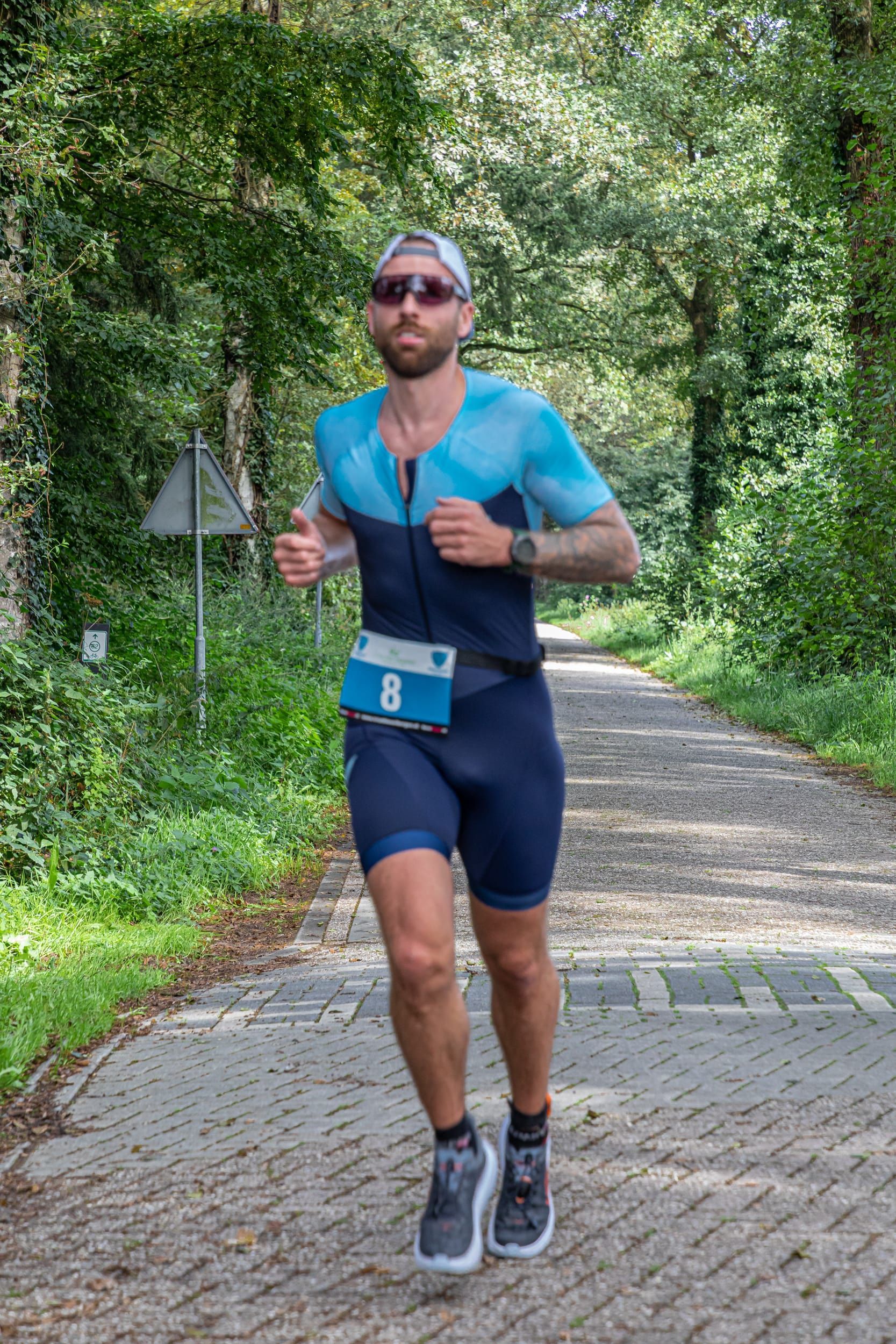 Een man rent over een stenen weg in het bos.