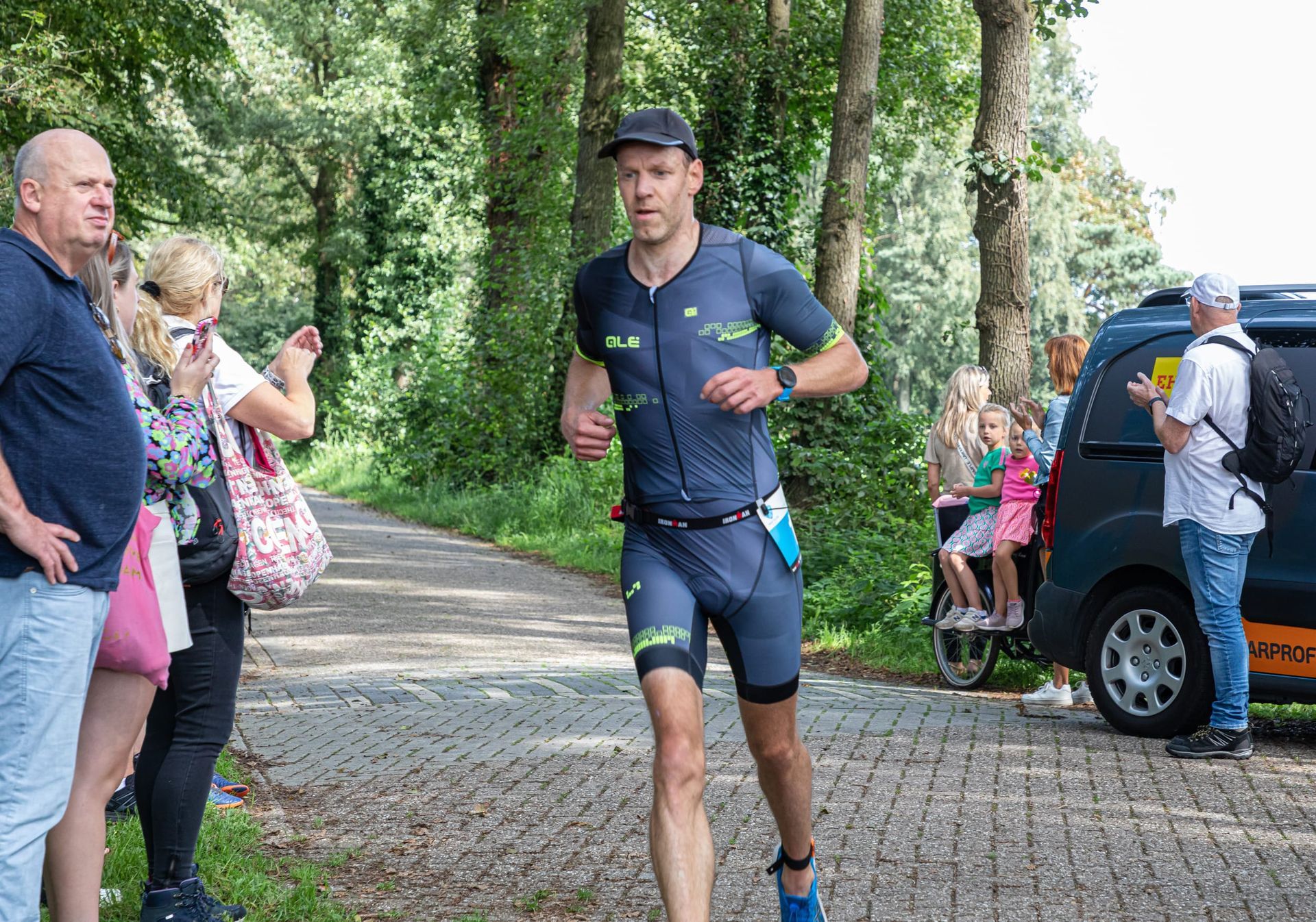 Een man in een triatlonpak rent over de weg.