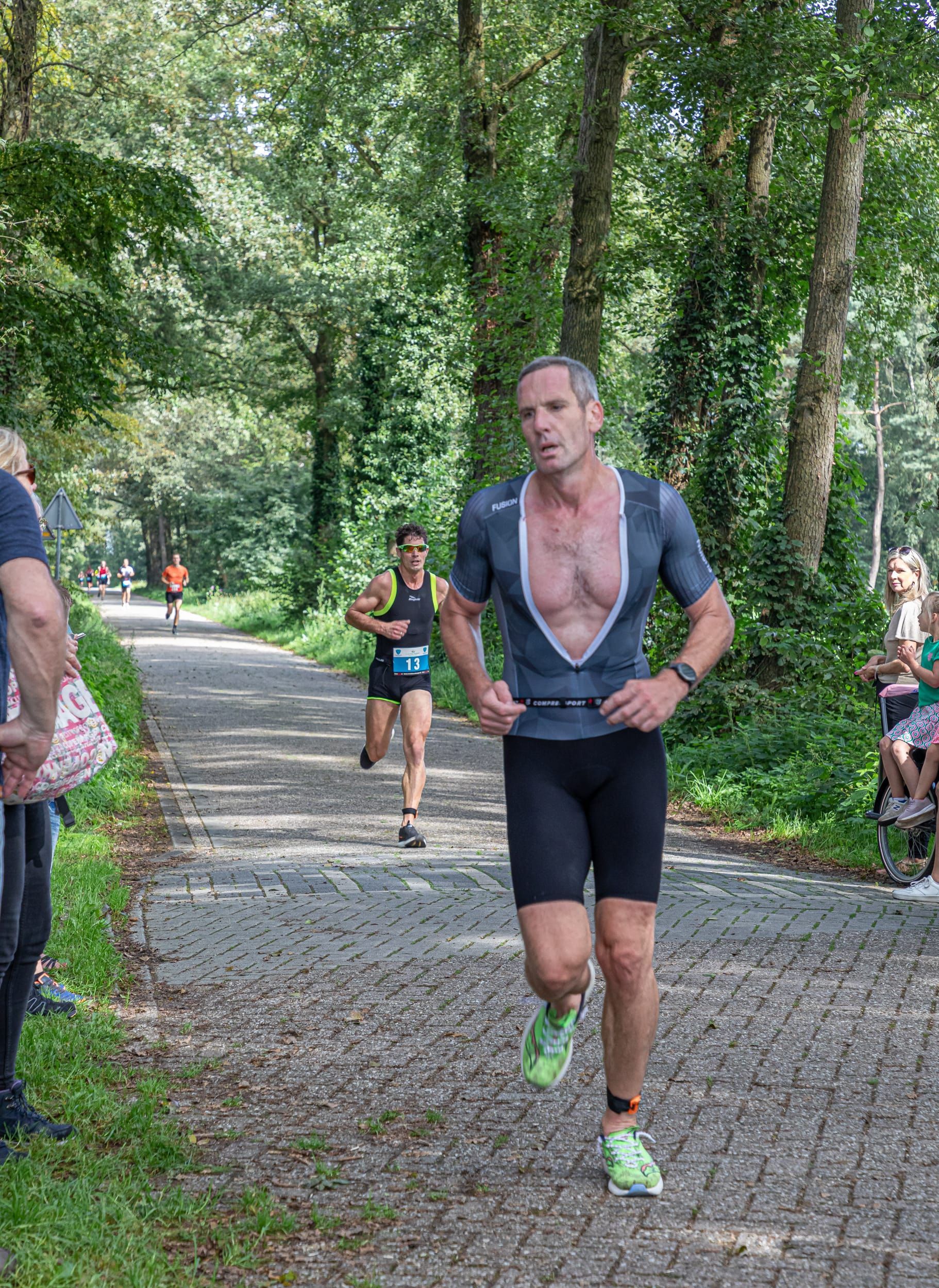 Een man rent over een pad in een park.