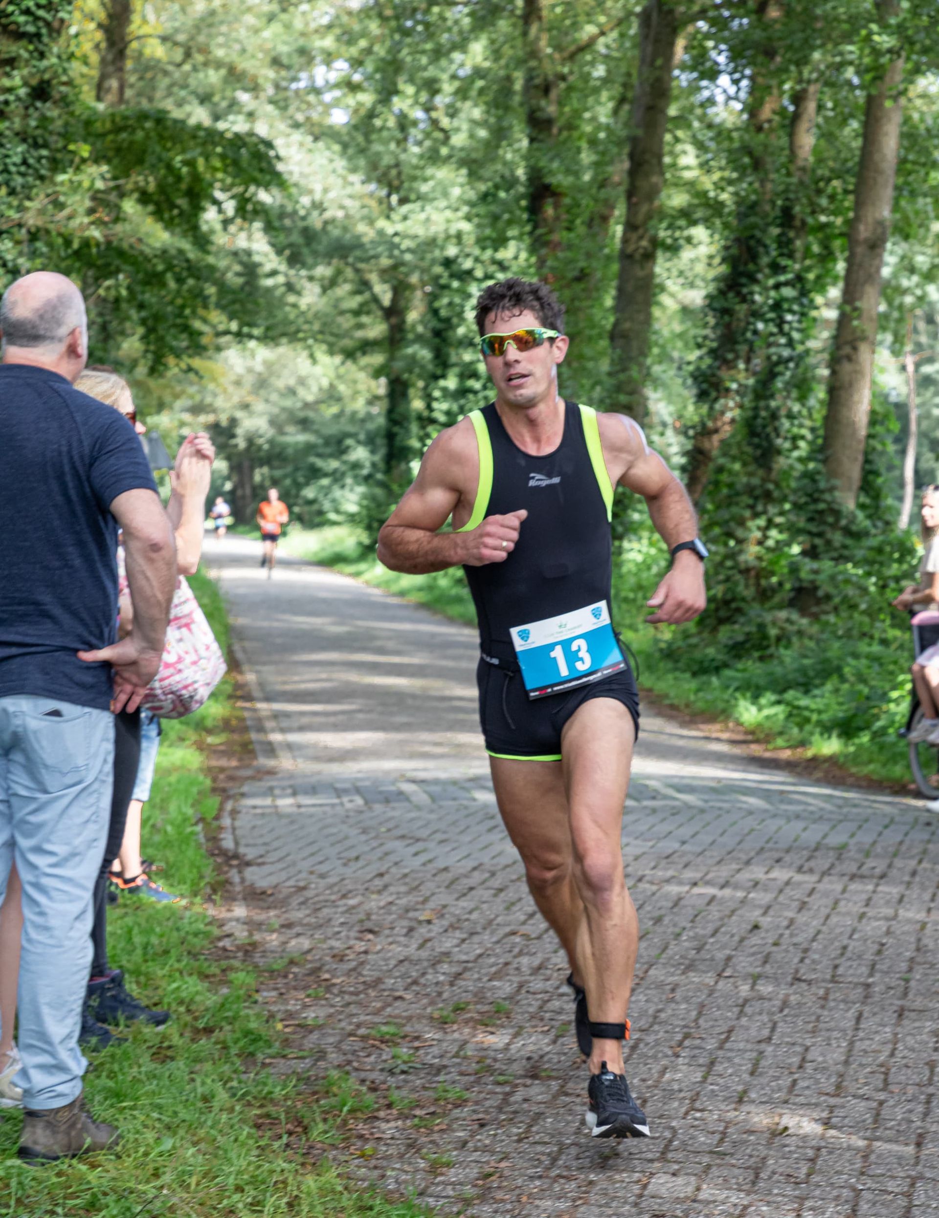 Een man rent een marathon op een stenen weg.