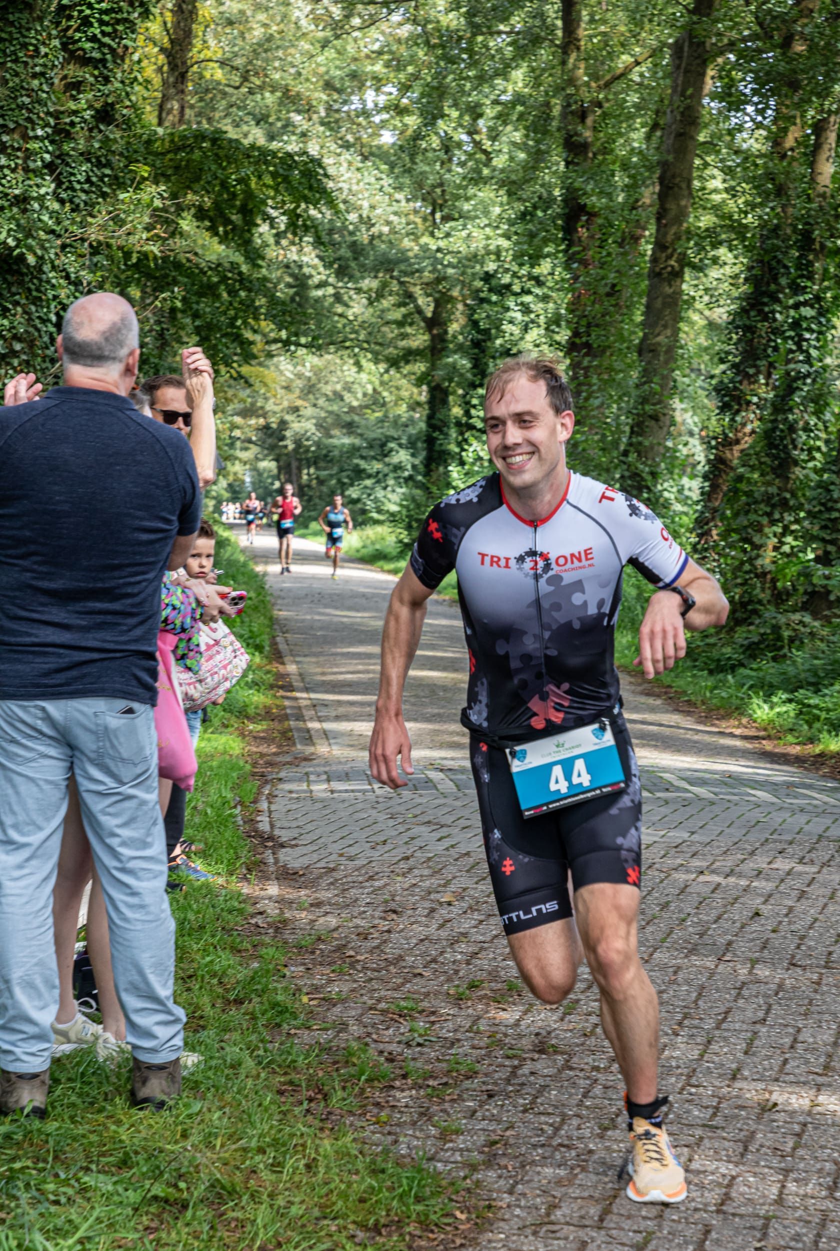 Een man rent over een pad in het bos.