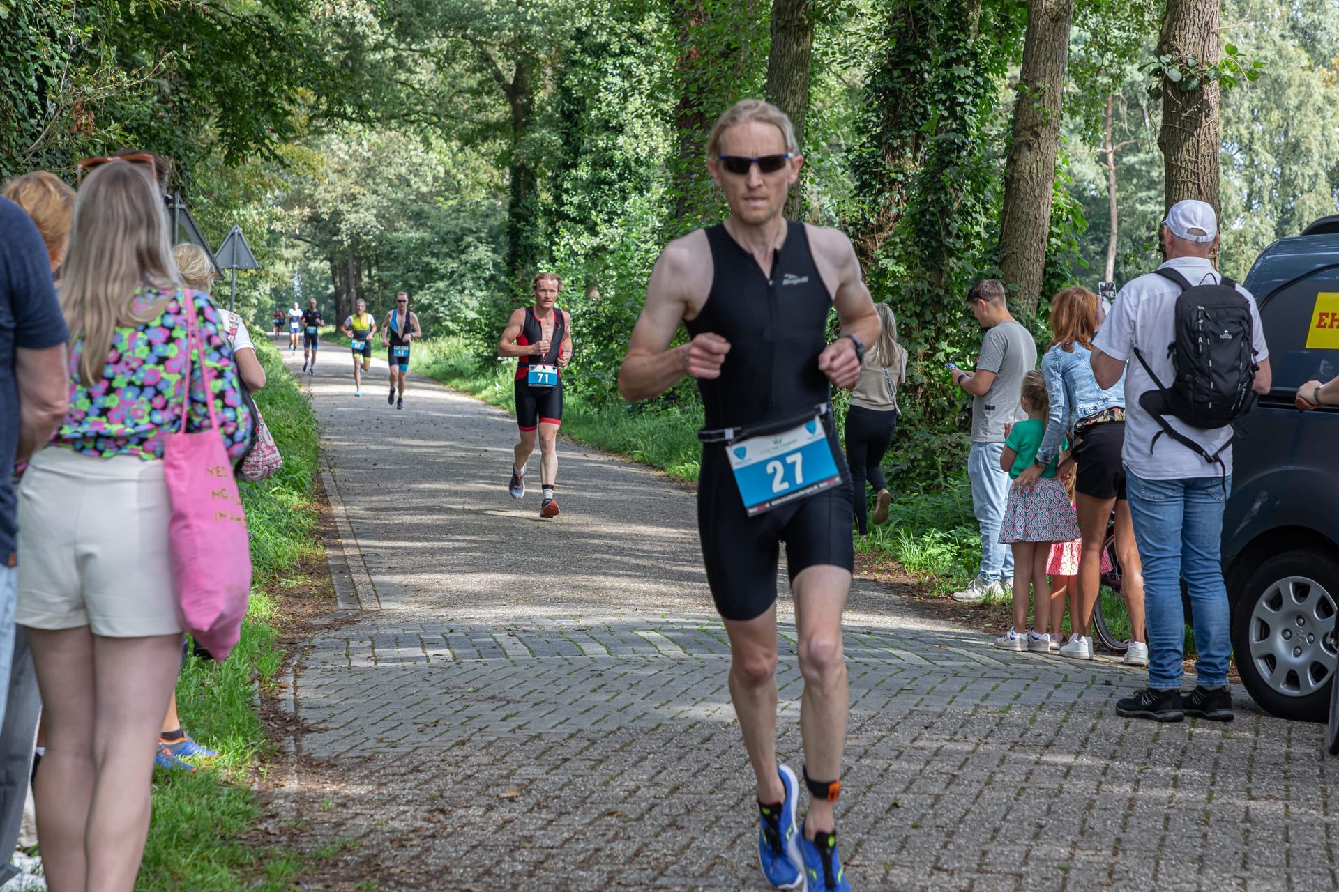 Een man rent een marathon op een geplaveide weg.