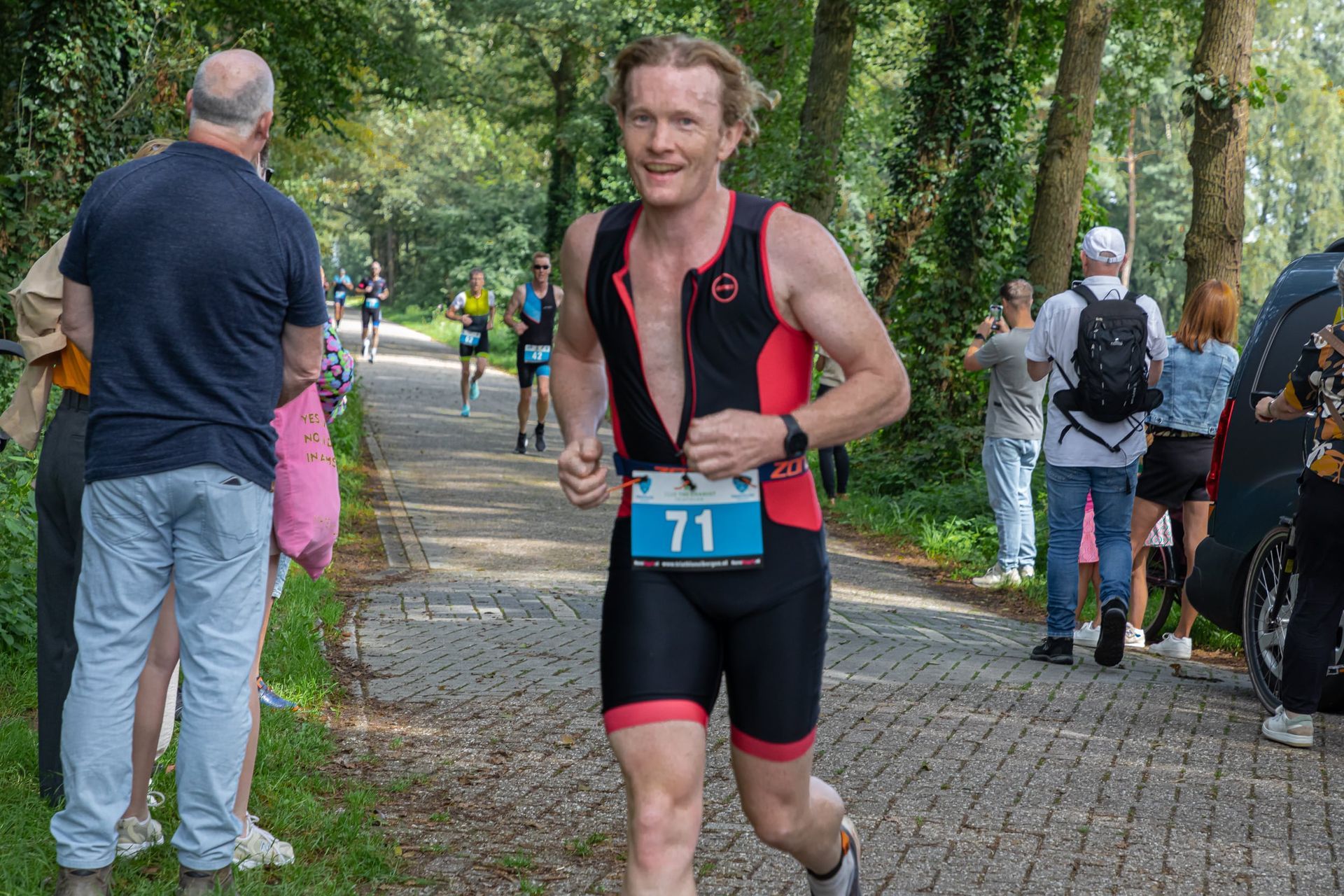 Een man rent mee in een triatlon met nummer 71 op zijn startnummer.