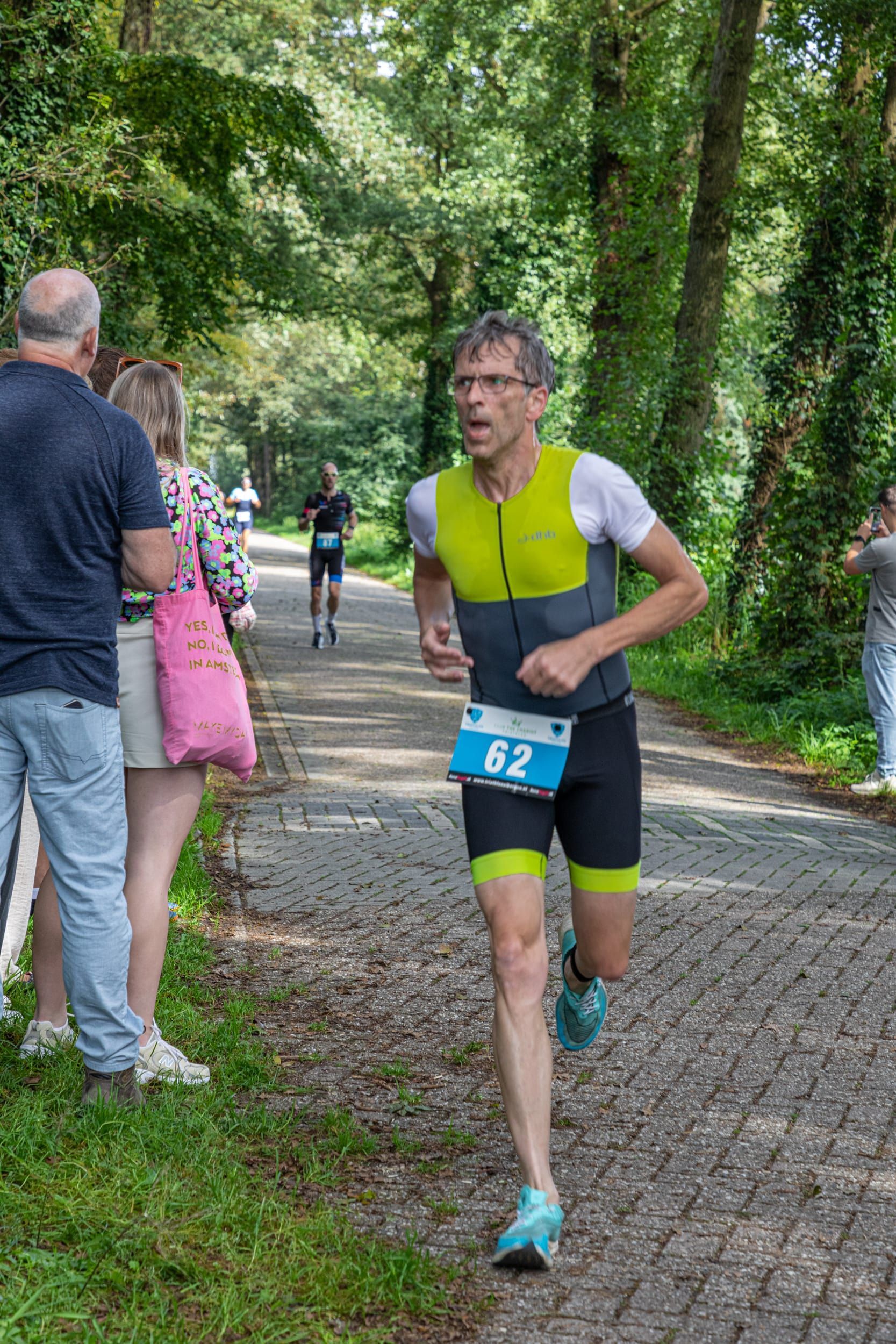 Een man rent een marathon op een geplaveide weg.