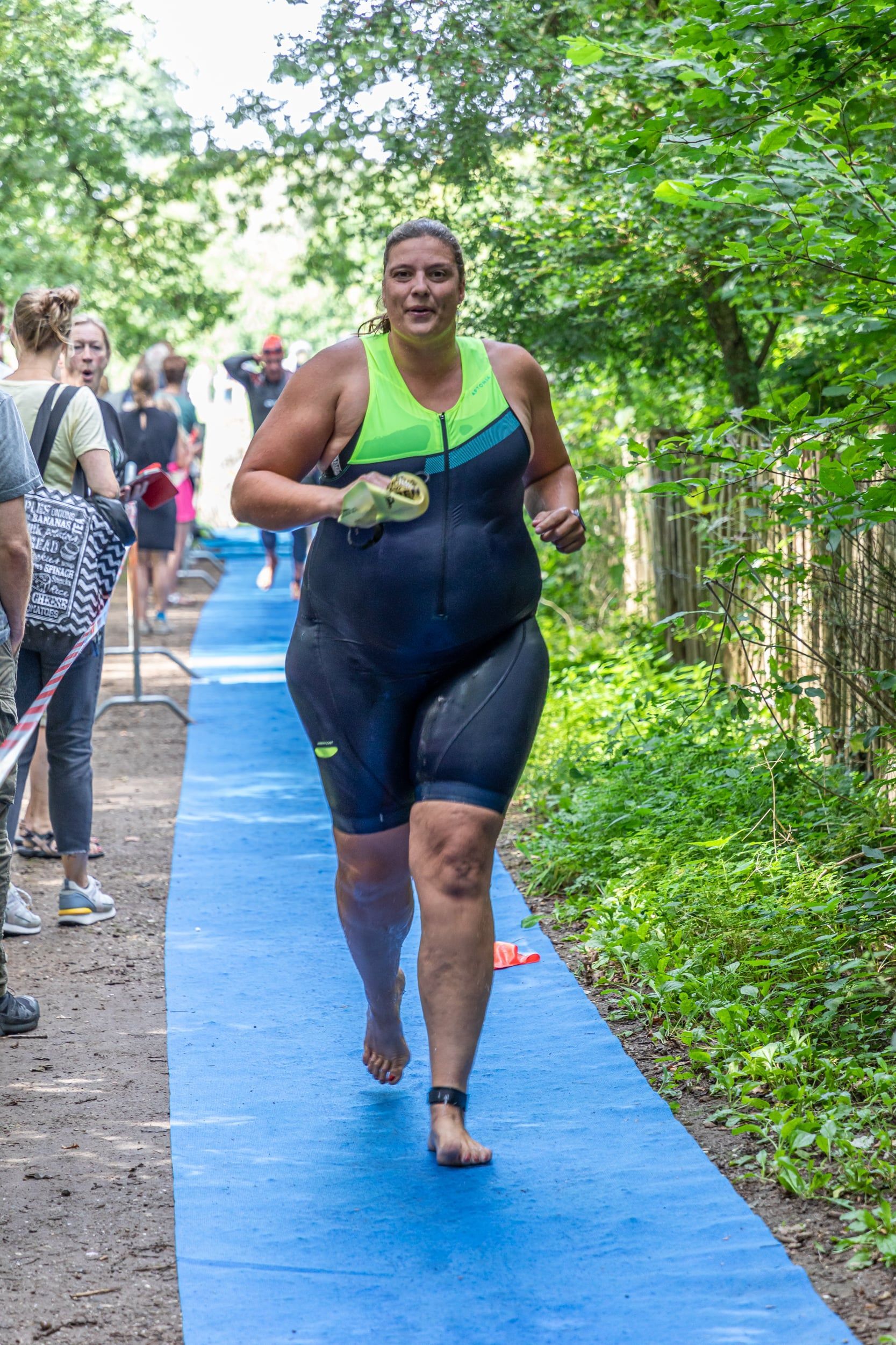 Een vrouw rent op een blauw pad in het bos.