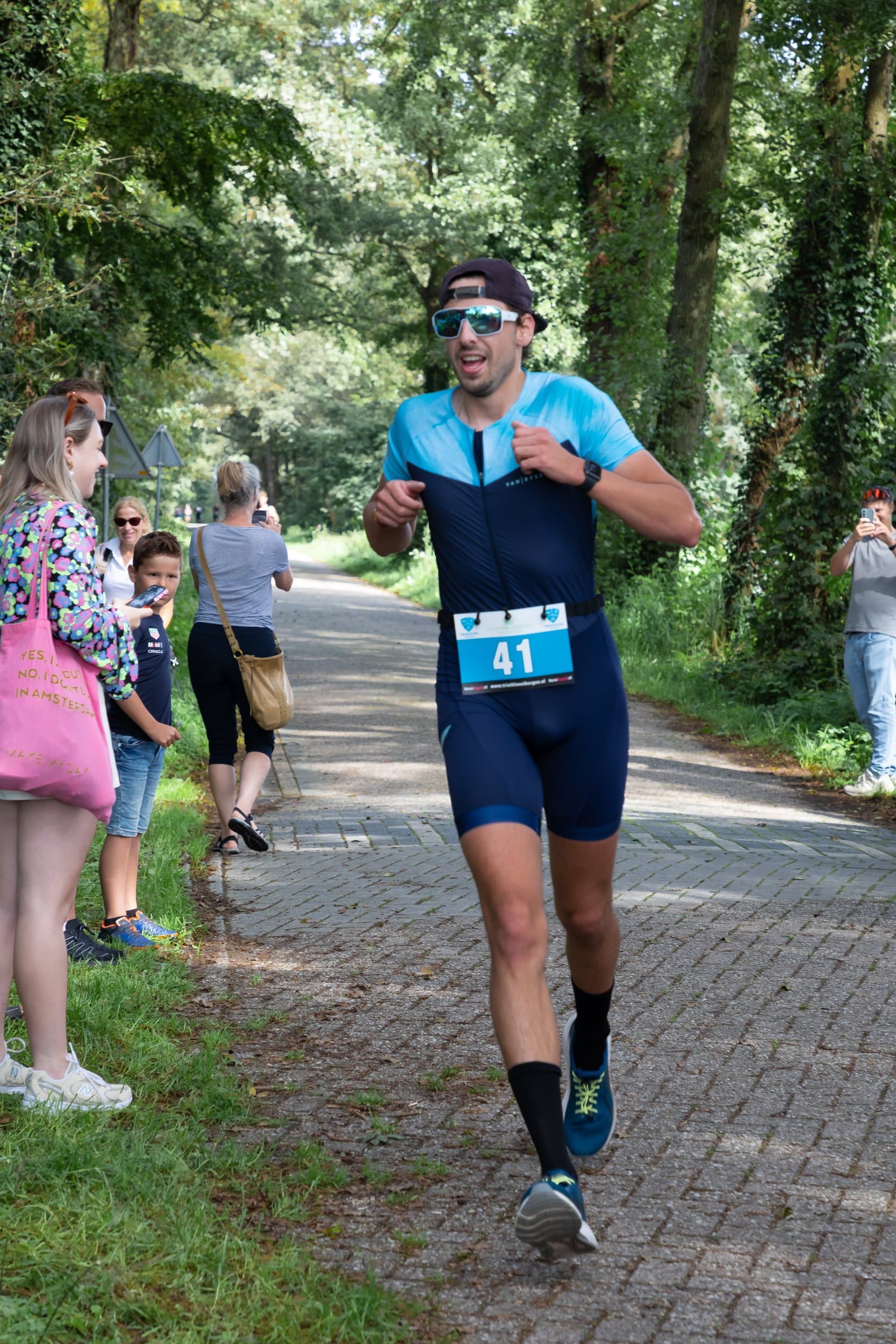 Een man in een triatlonpak rent over de weg.