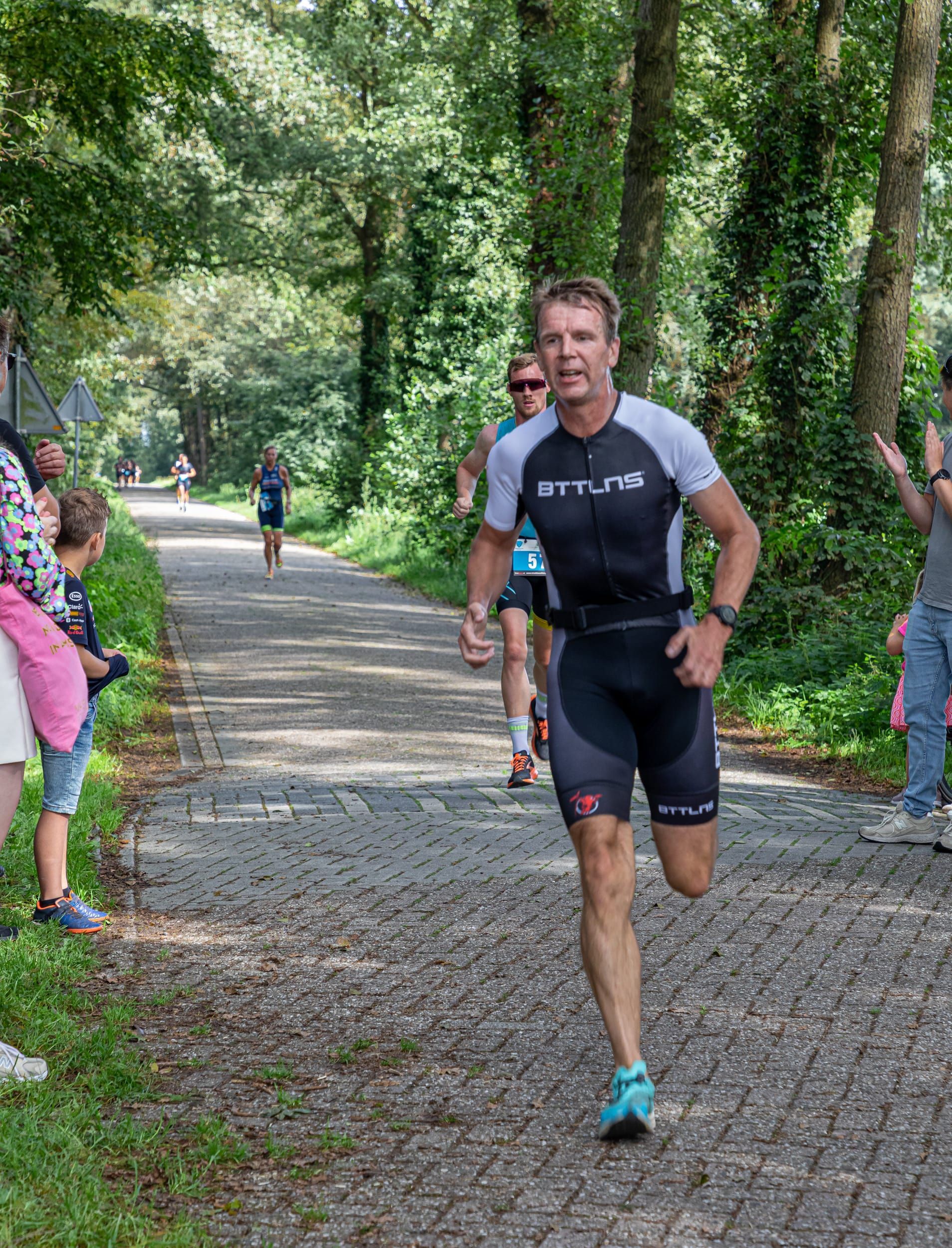 Een man rent over een geplaveide weg in het bos.