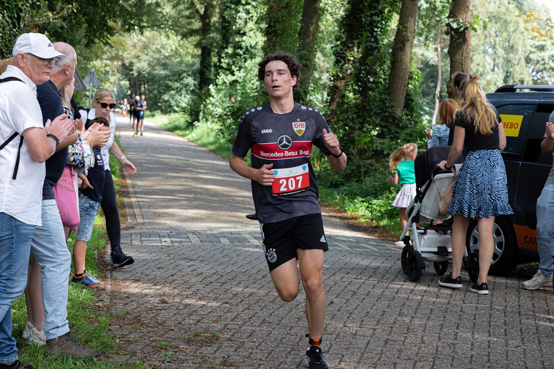 Een man rent een marathon op een geplaveide weg.