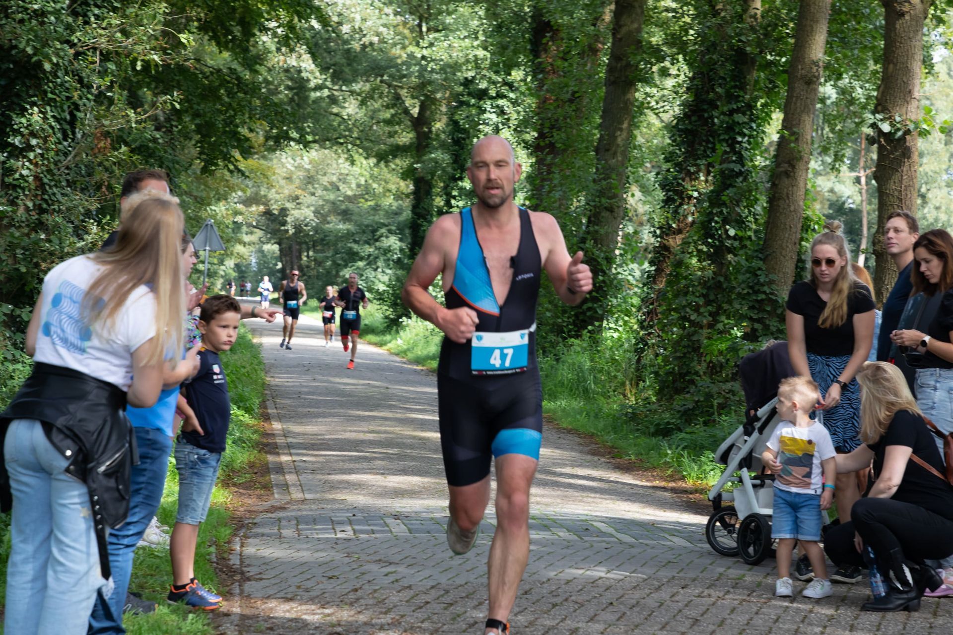 Een man in een triatlonpak rent over de weg.