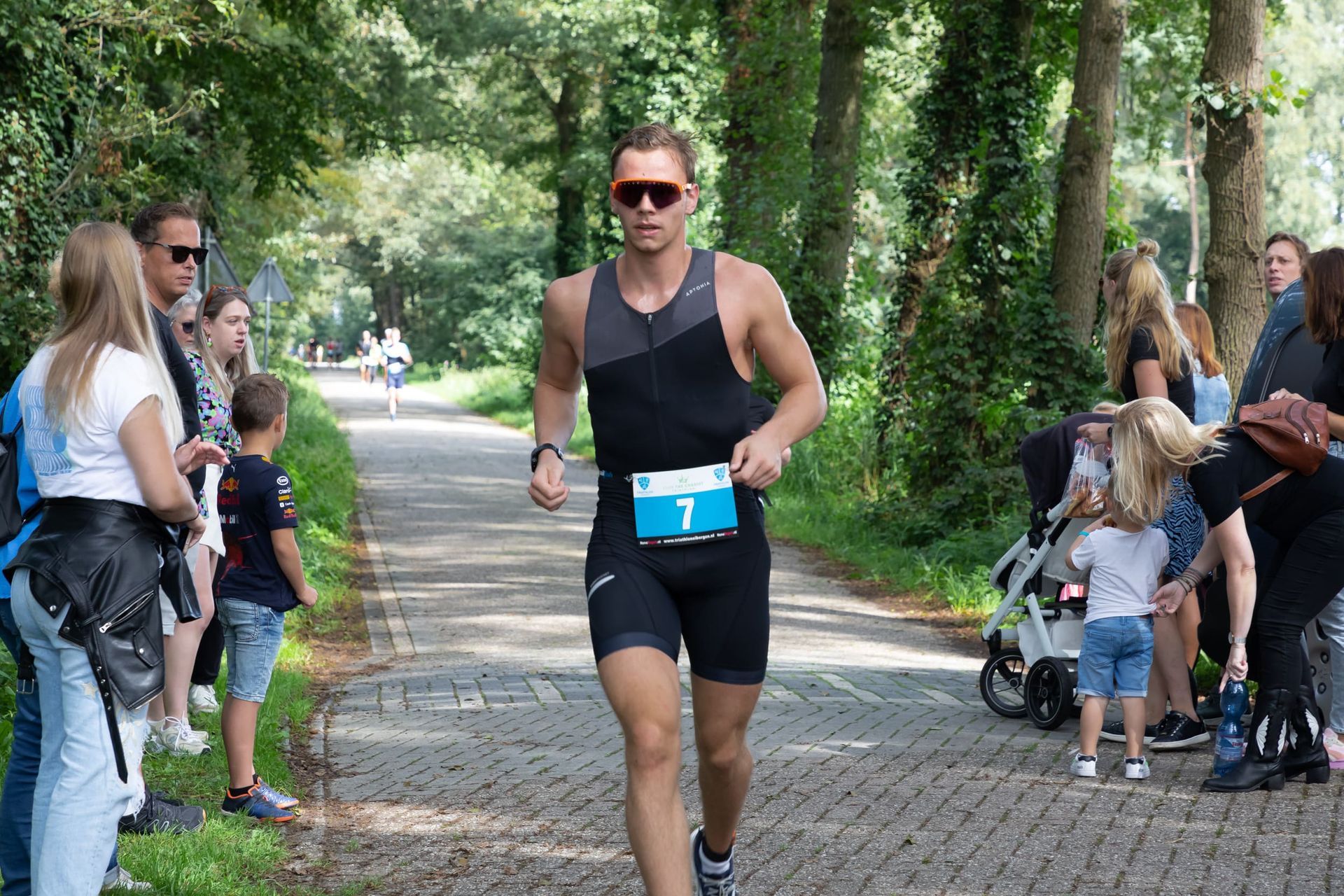 Een man met een zonnebril rent over de weg.