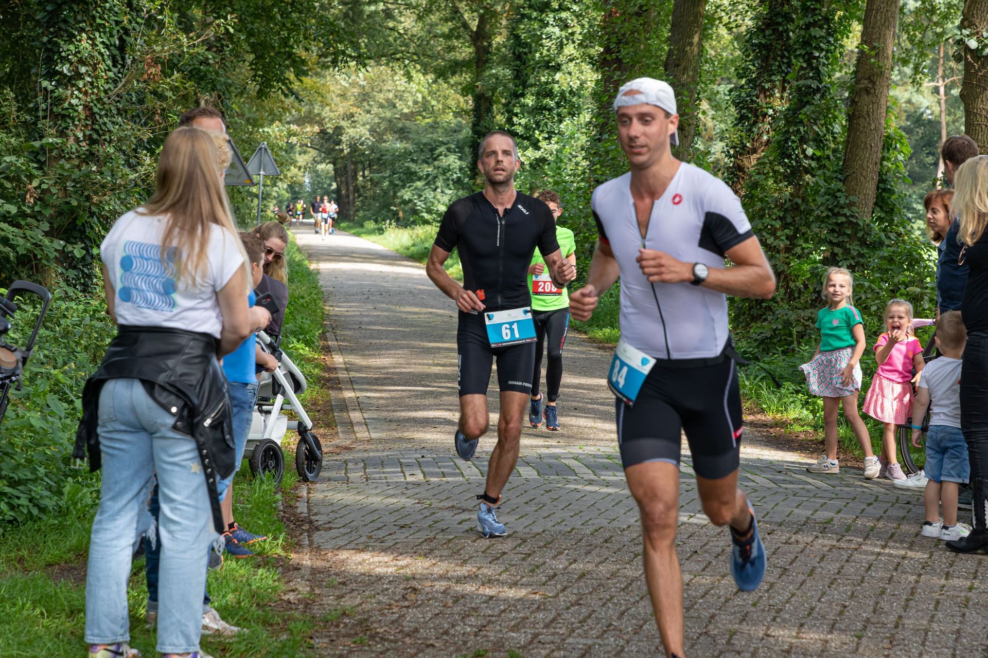 Een groep mannen rent over een pad in een park.