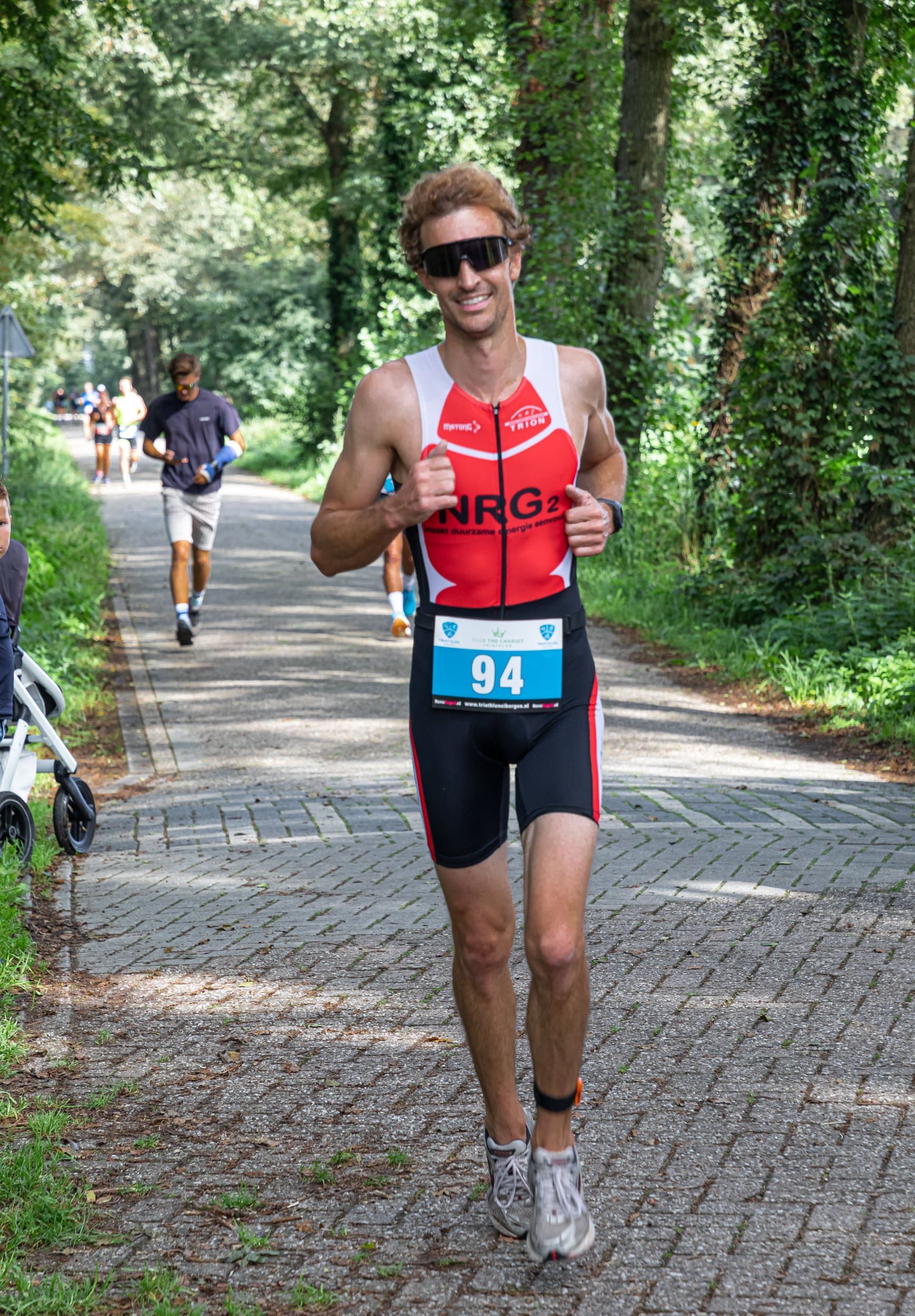 Een man in een triatlonpak rent over de weg.