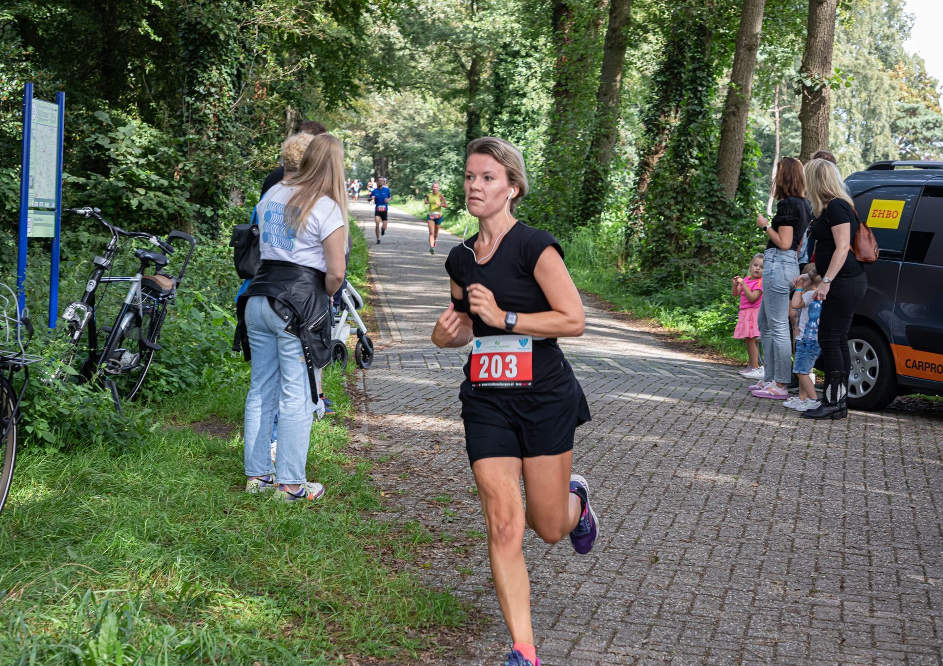 Een vrouw rent over een pad in het bos.