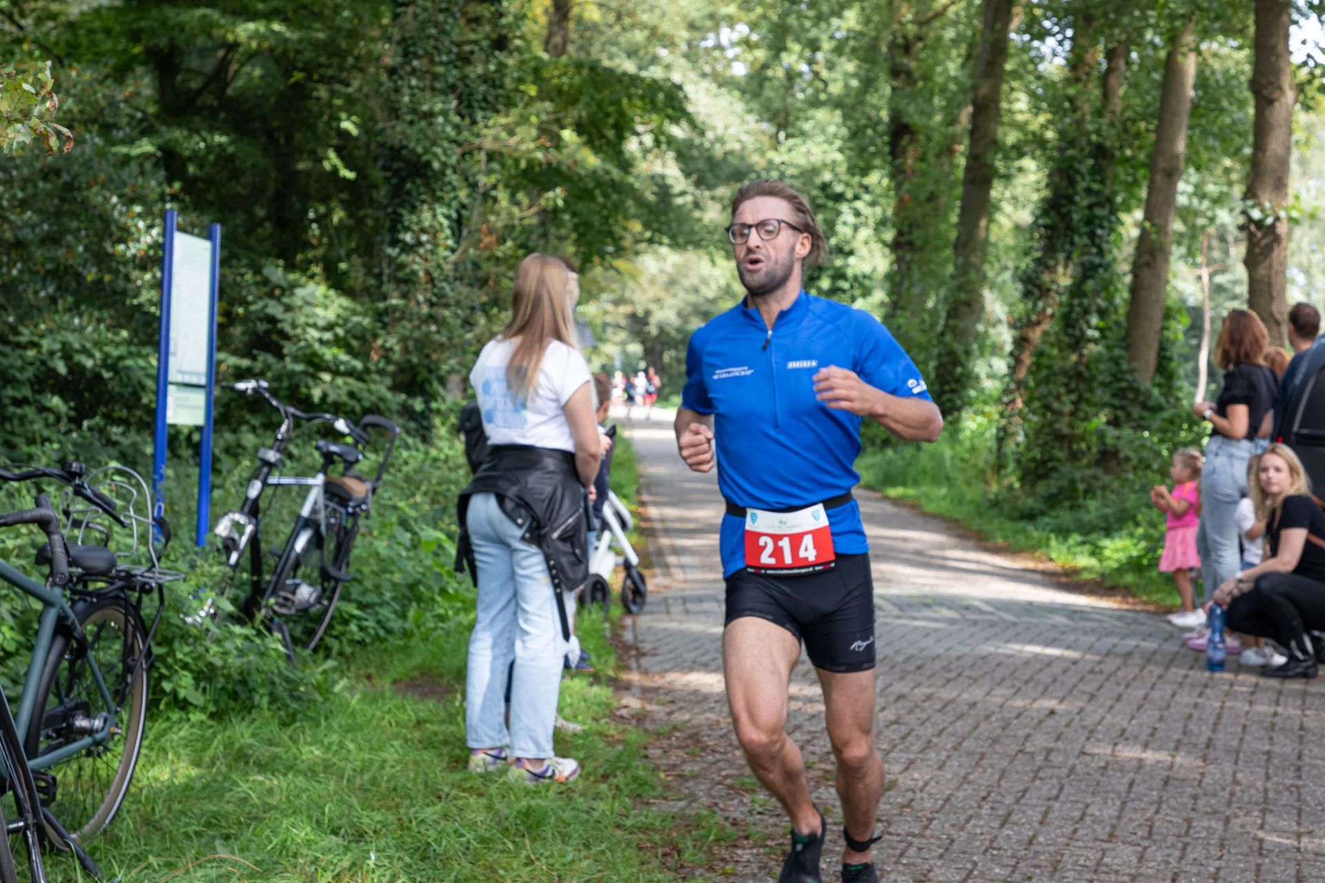 Een man rent over een pad in het bos.