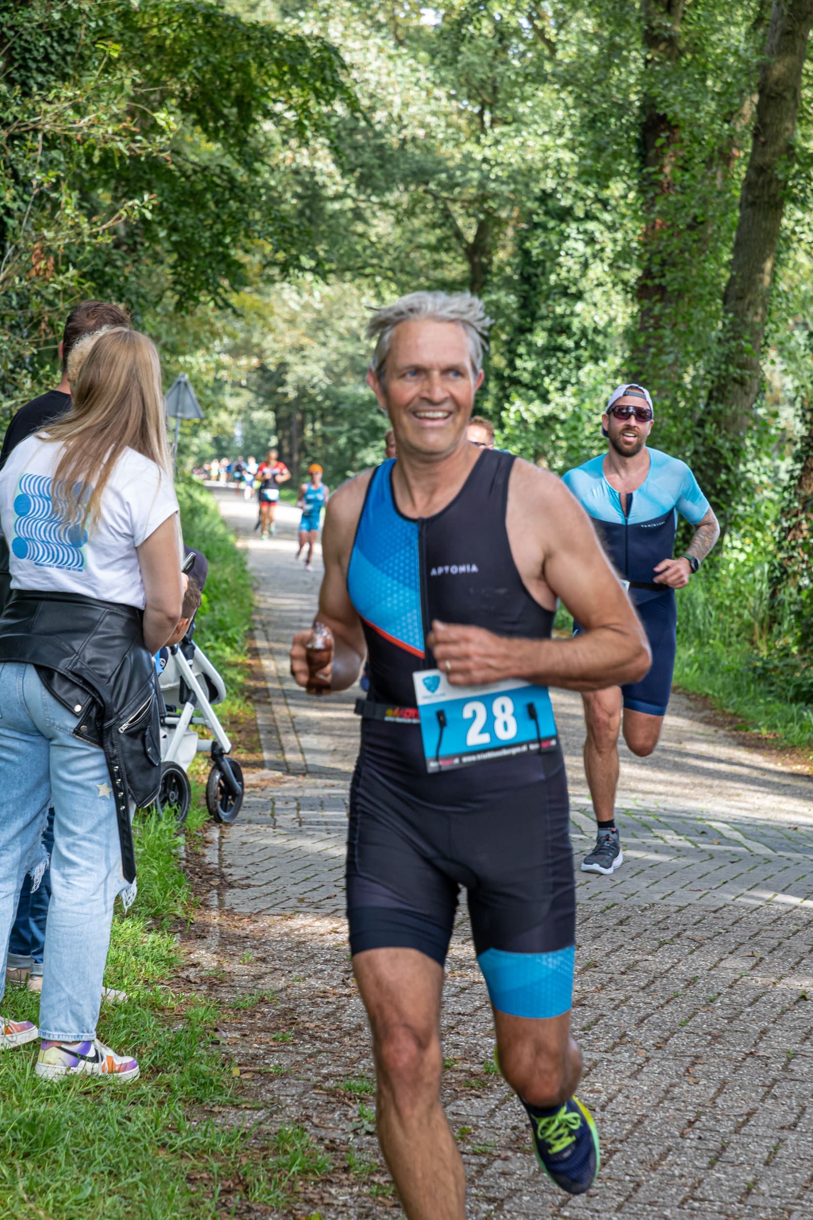 Een man rent mee in een triatlon op een onverharde weg.