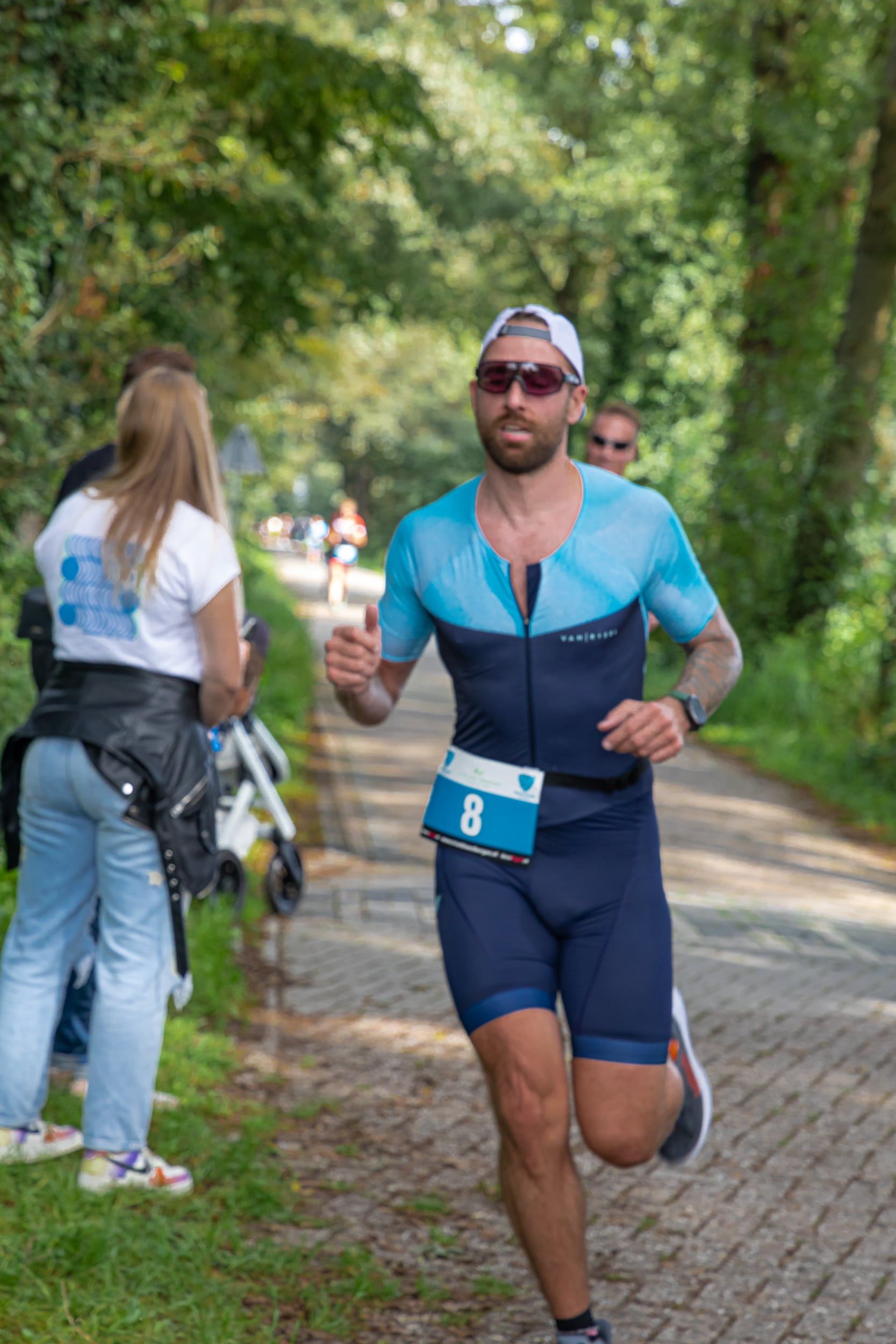 Een man in een triatlonpak rent over de weg.