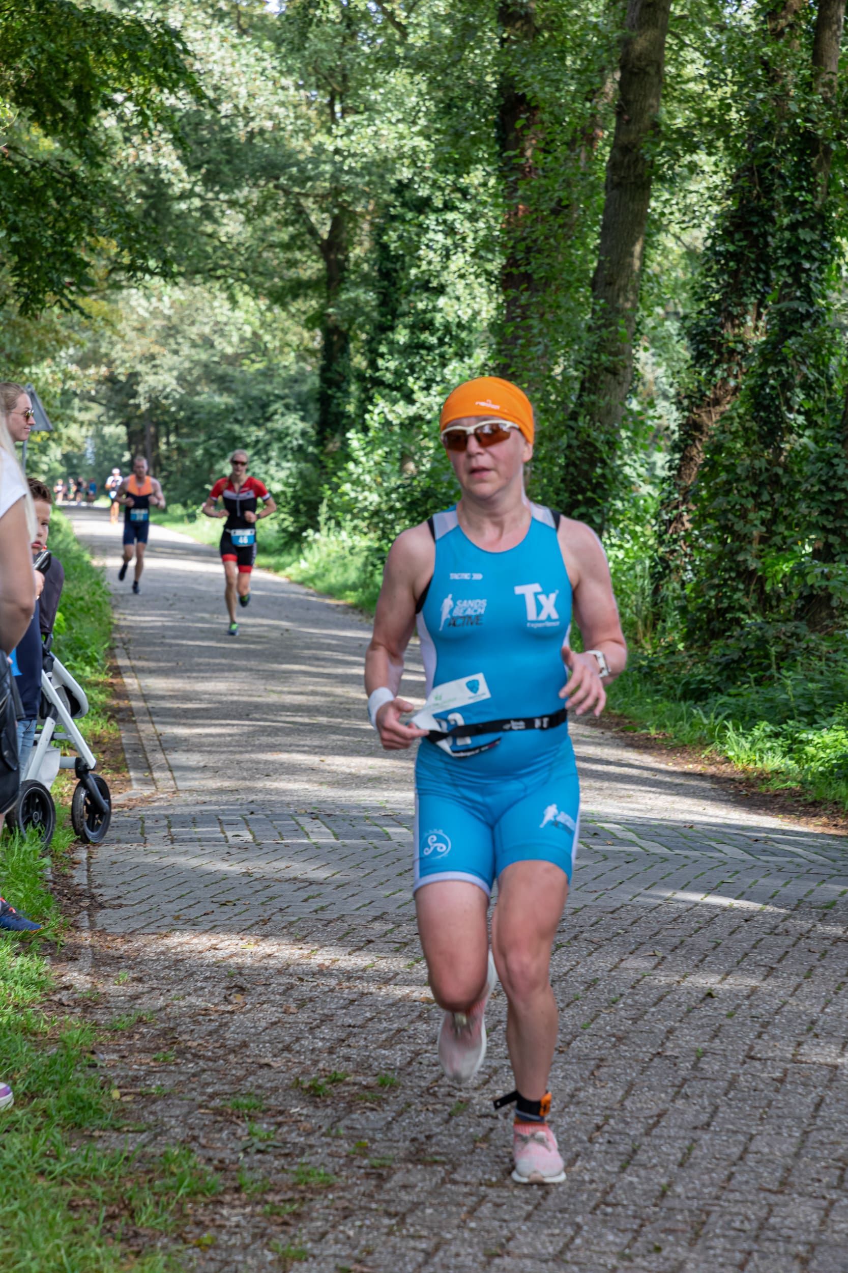 Een vrouw rent een triatlon op een stenen weg.