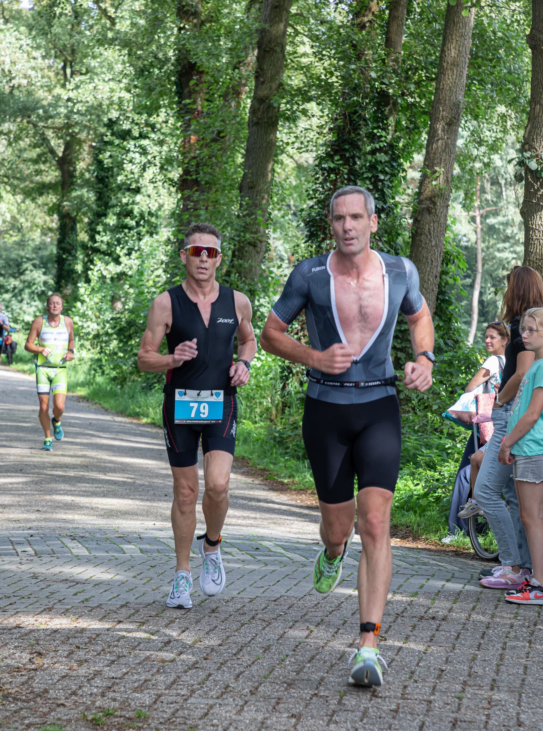 Een groep mannen rent over een weg in het bos.