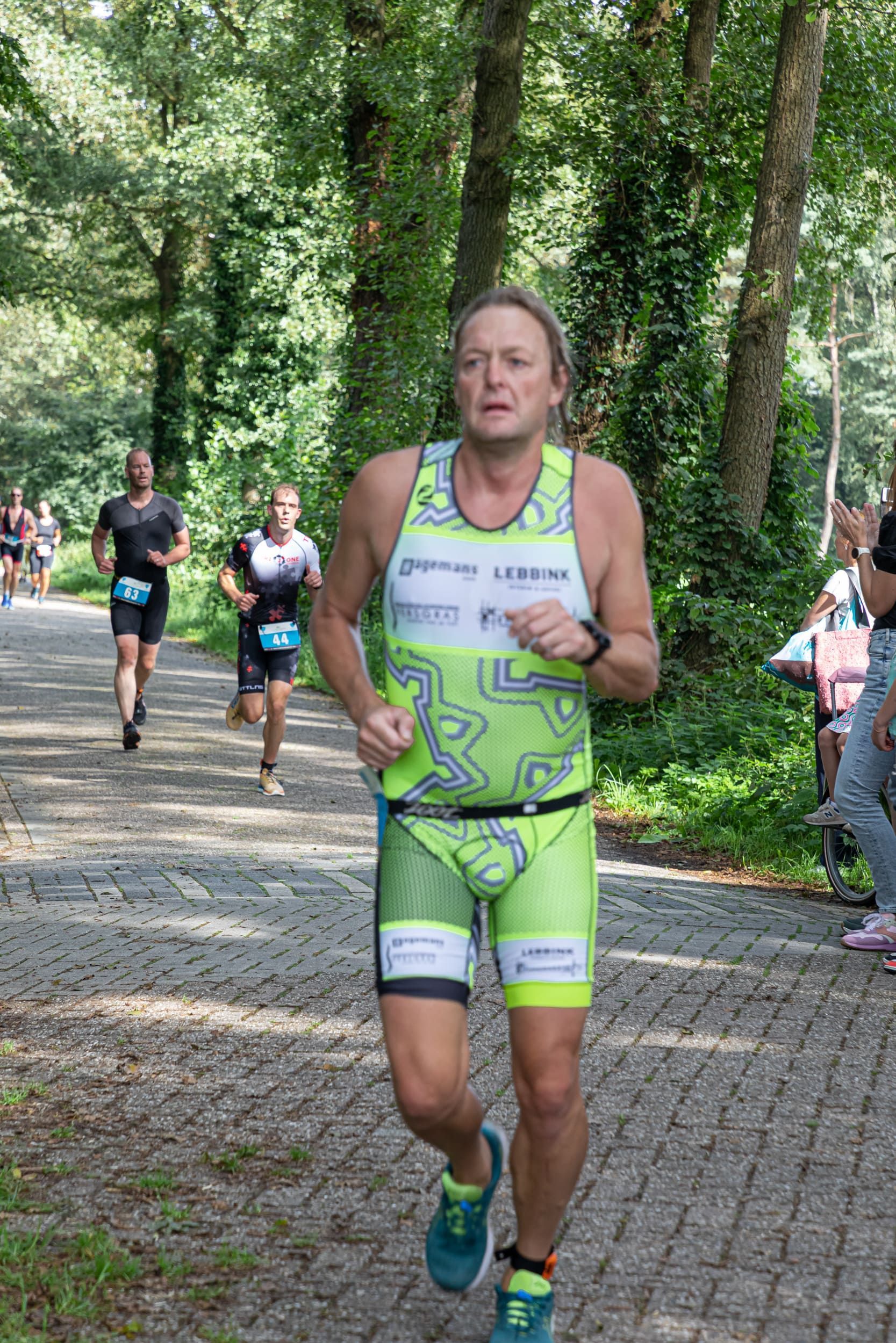 Een man rent in een triatlon in het bos.