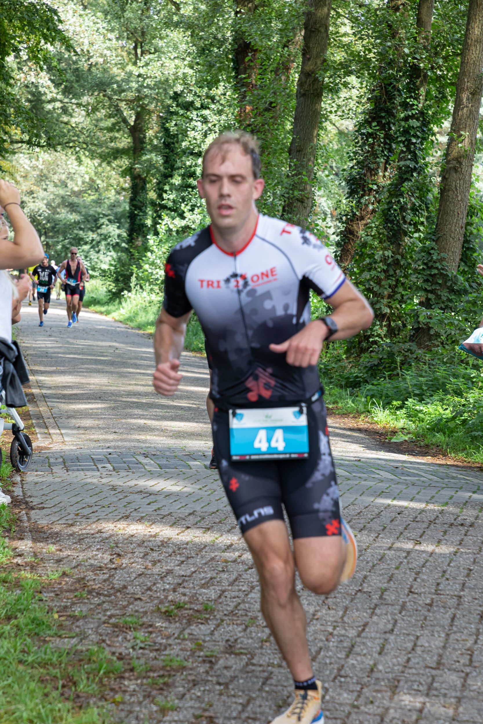 Een man rent over de weg met nummer 44 op zijn startnummer.