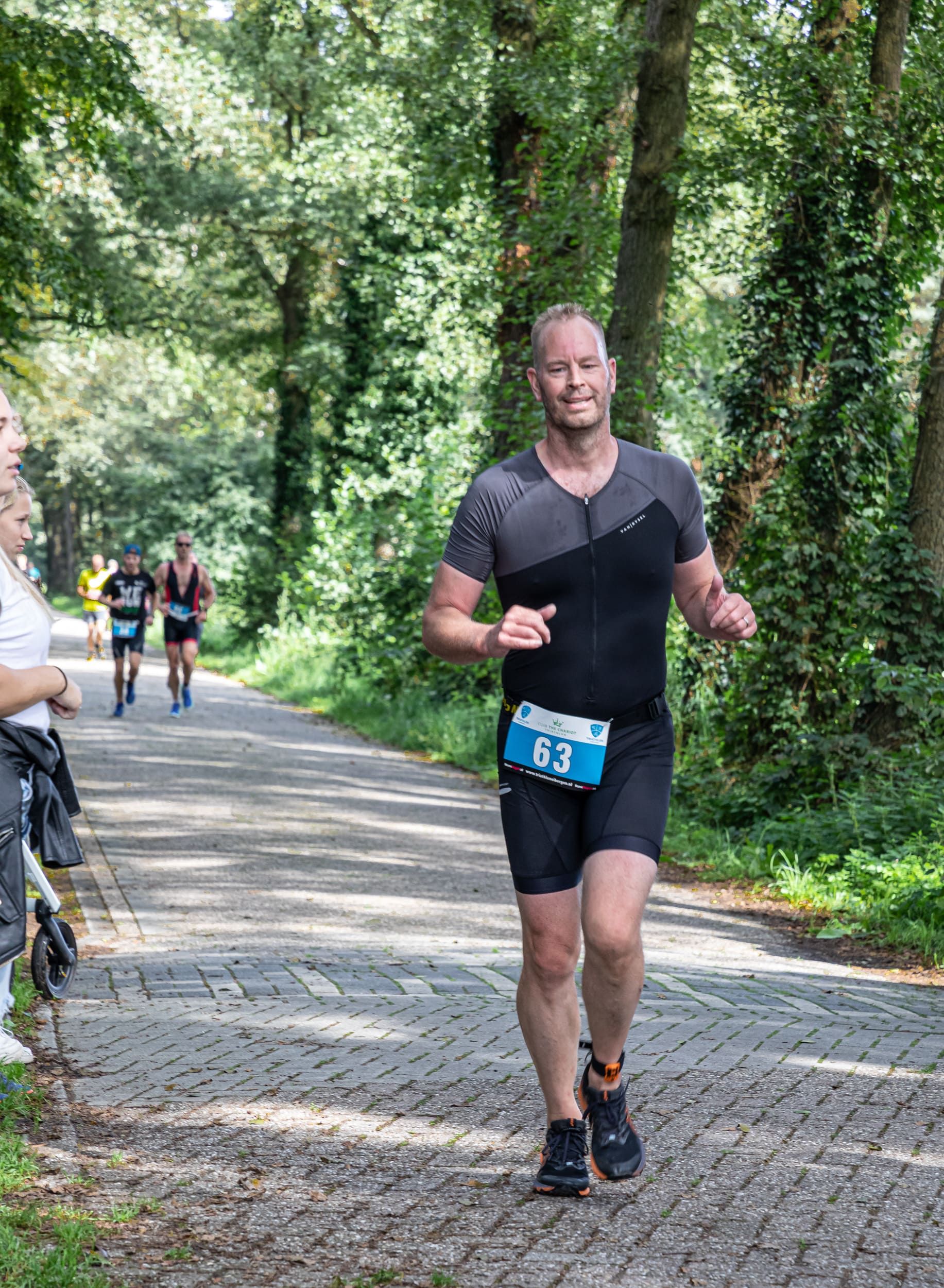 Een man rent over een weg in het bos.