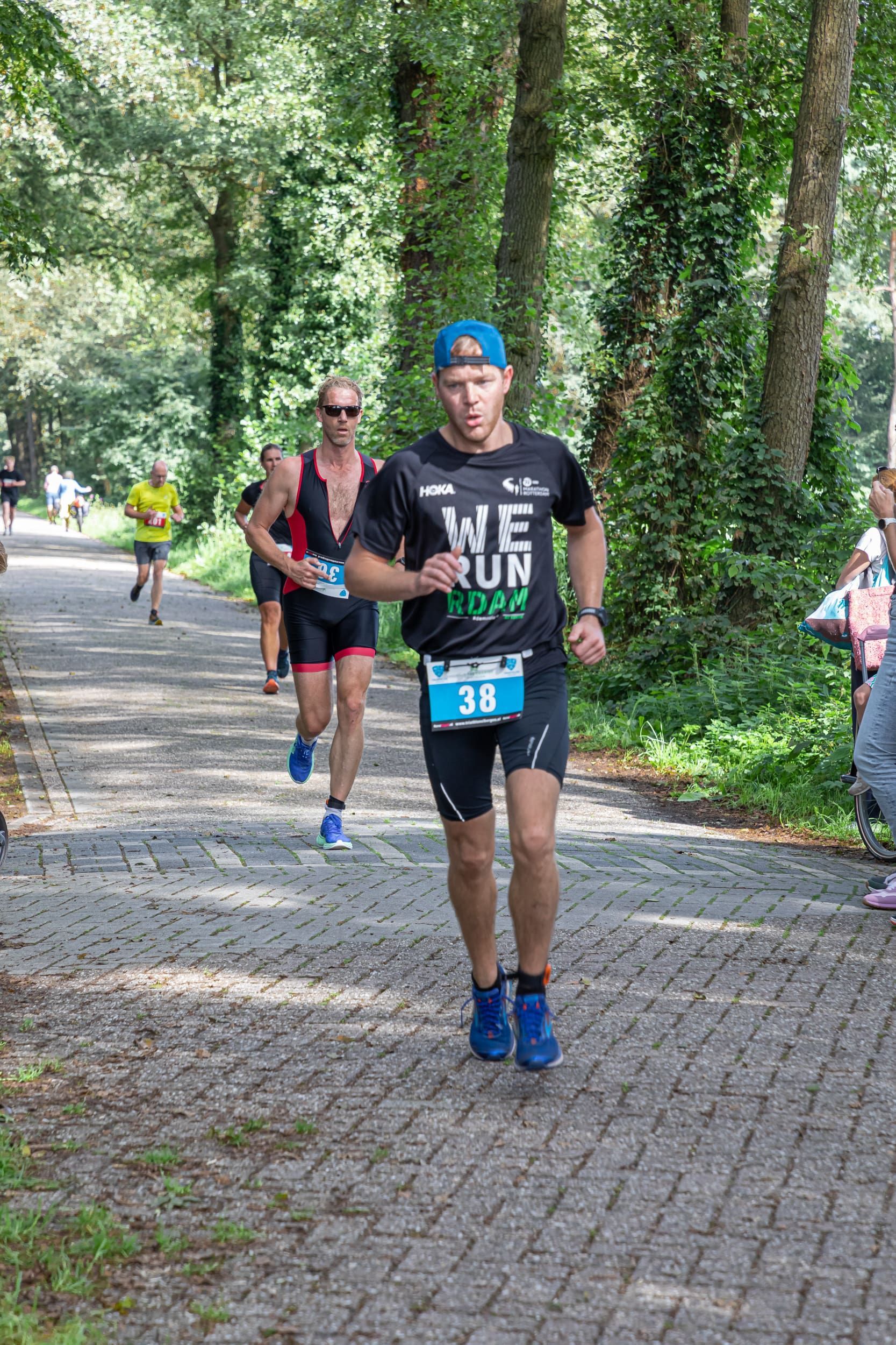 Een groep mensen rent een marathon op een stenen weg.
