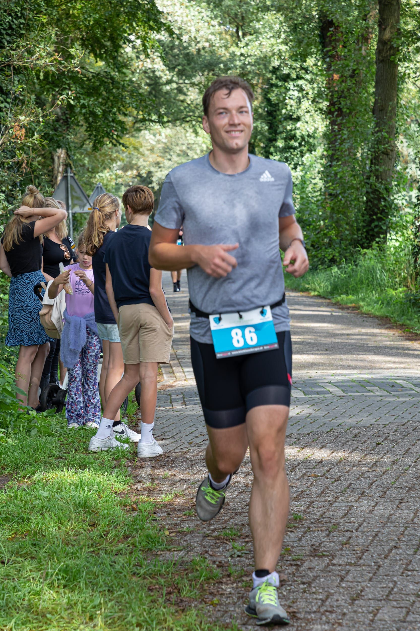 Een man rent over een pad in een park.