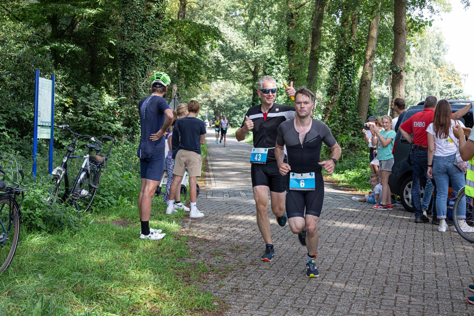 Een groep mannen rent over een pad in het bos.