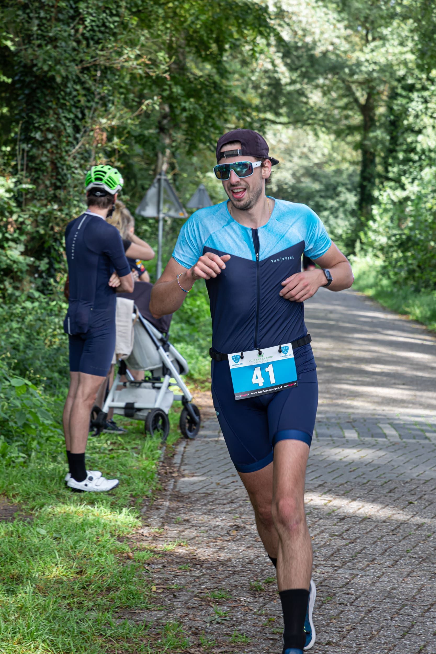 Een man rent over de weg, met op de achtergrond een kinderwagen.
