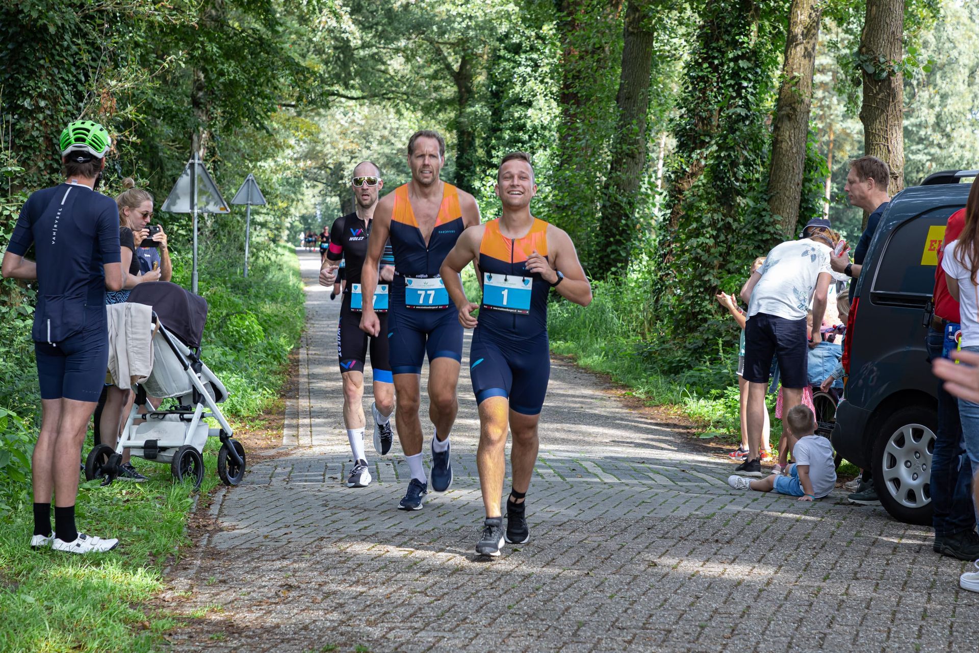 Een groep mannen rent over een geplaveide weg.