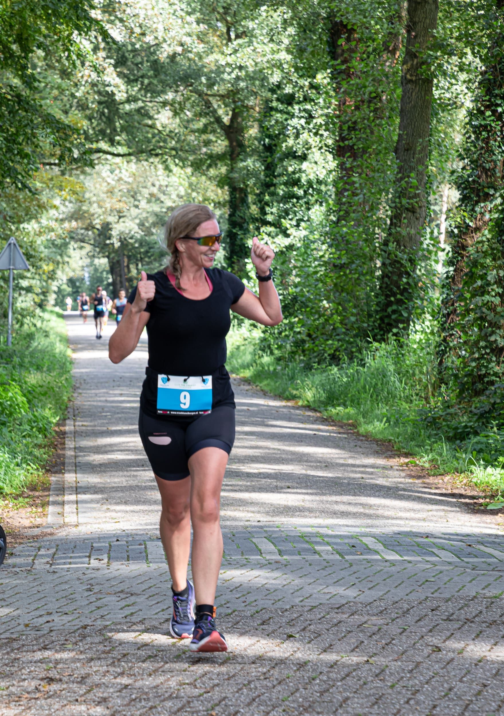 Een vrouw rent over een weg in het bos.
