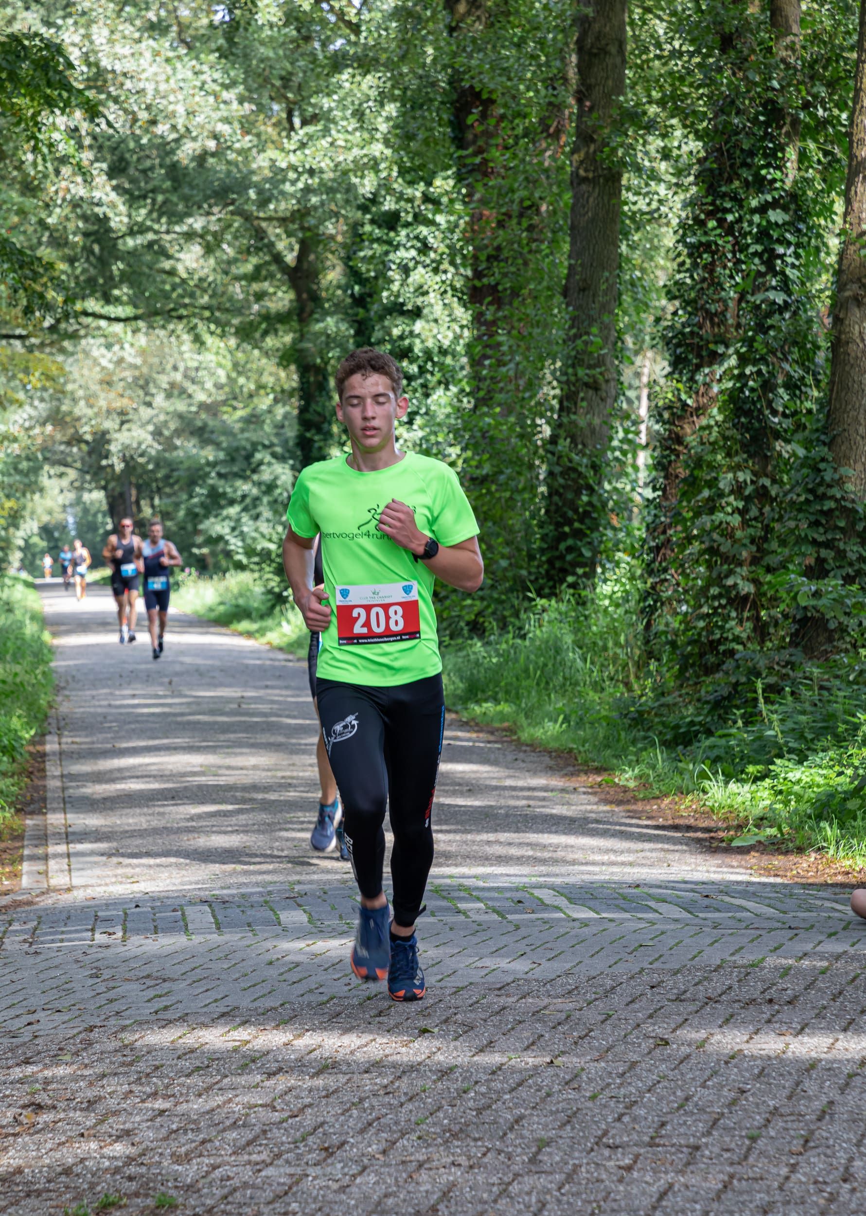 Een man in een groen shirt rent over de weg.