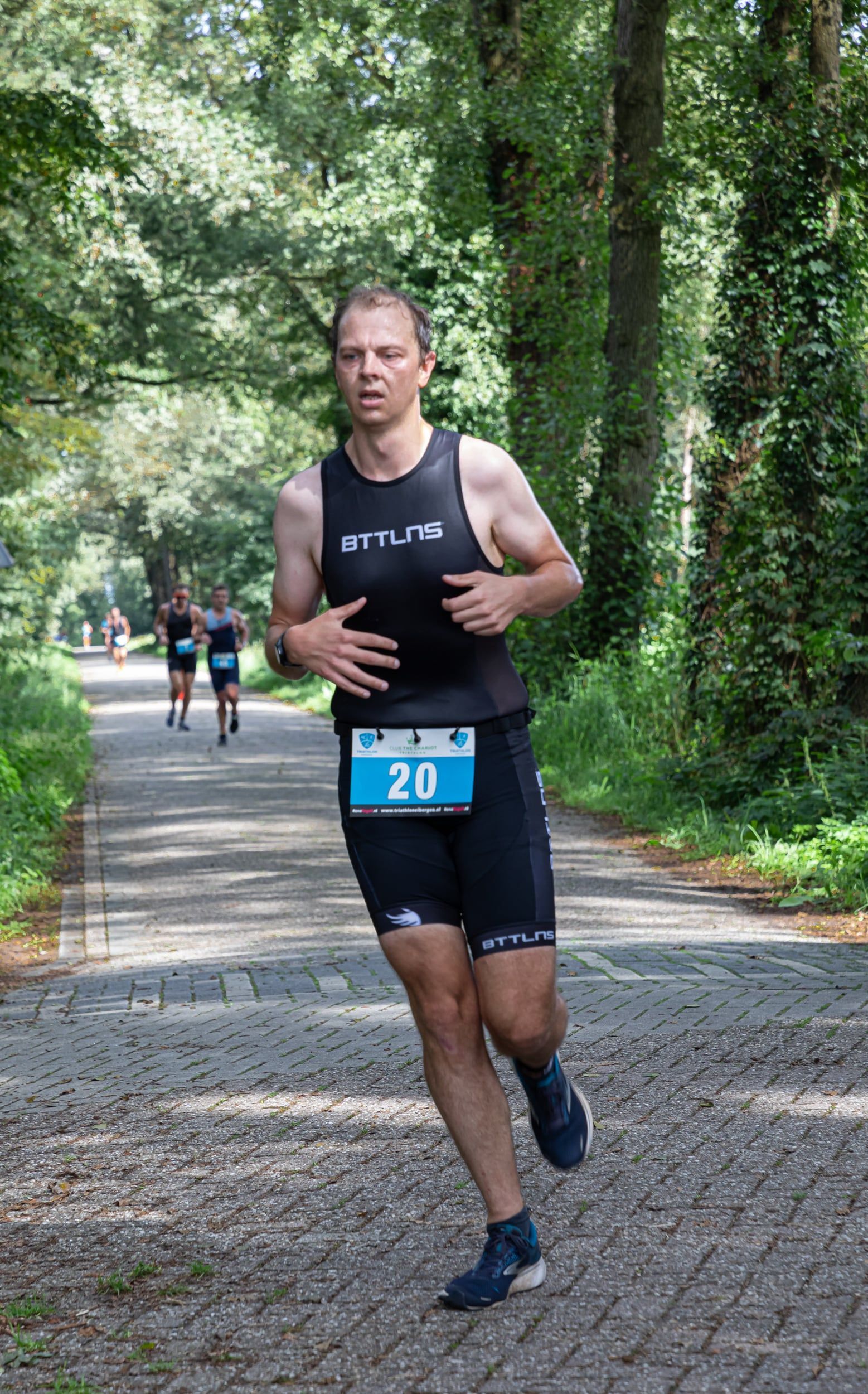 Een man rent een marathon op een onverharde weg.