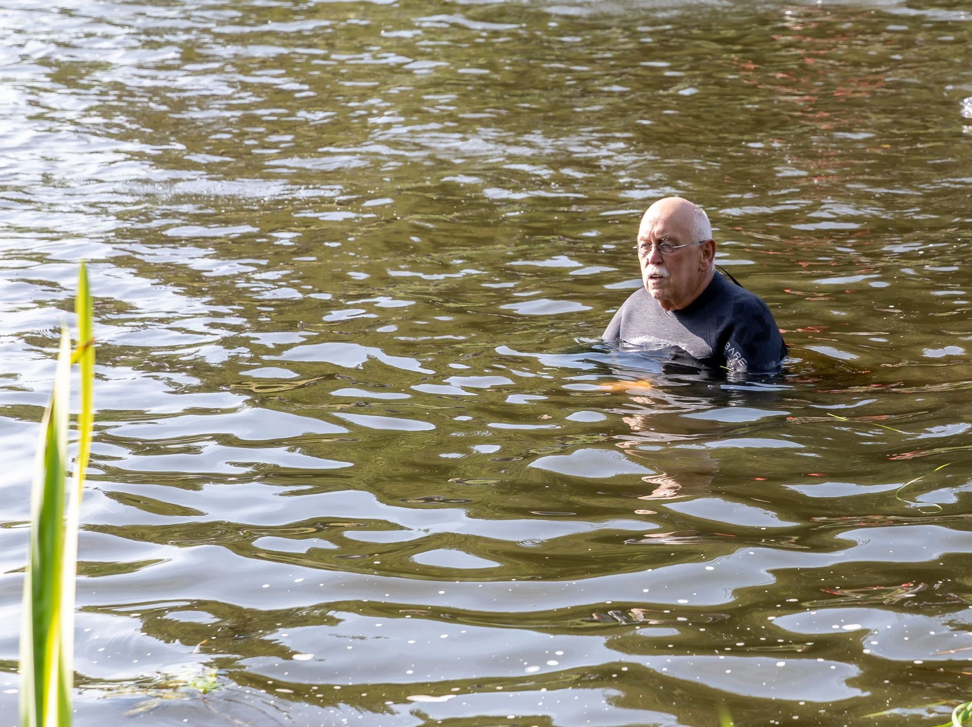 Een man in een wetsuit zwemt in een meer.