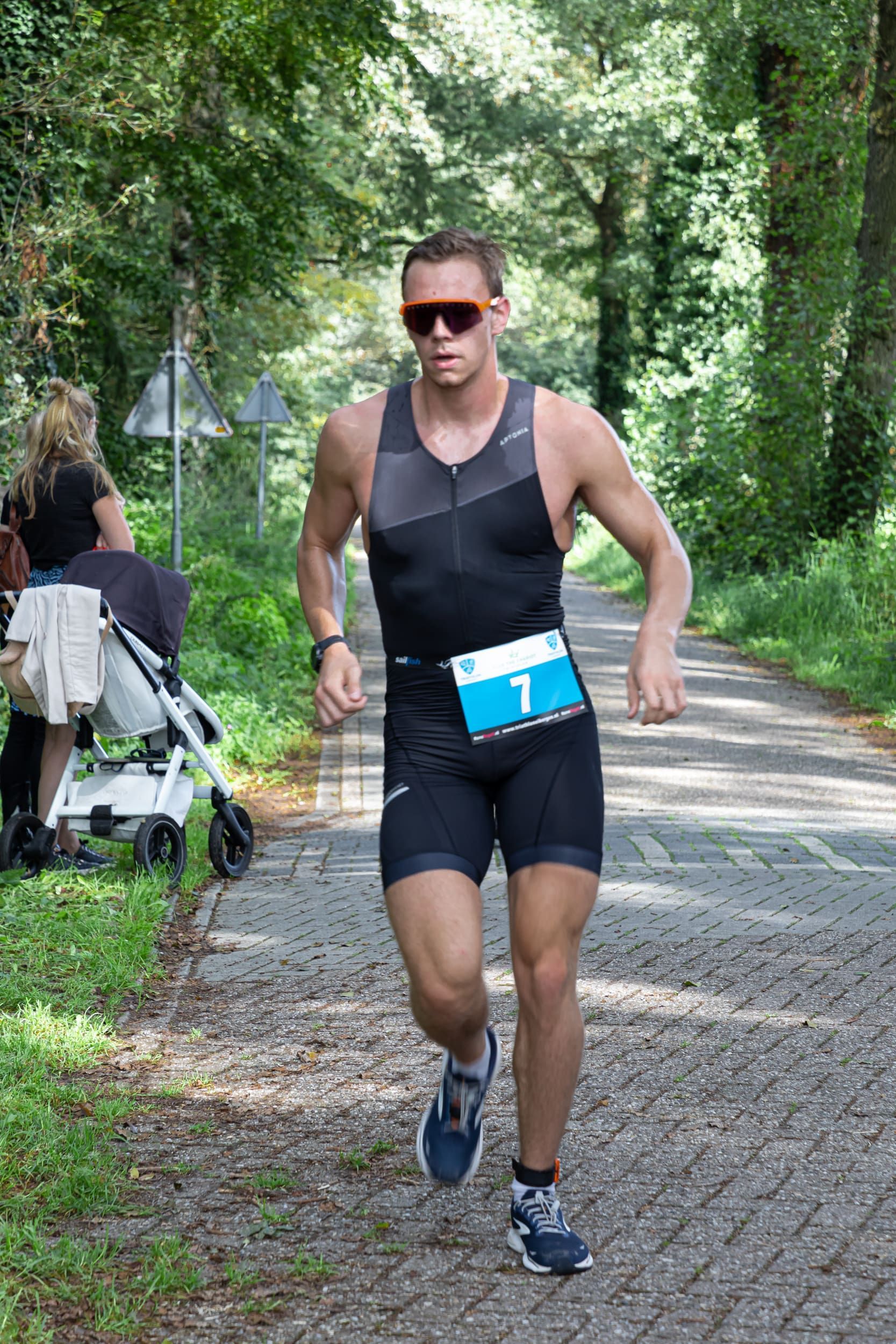 Een man rent over de weg, met op de achtergrond een kinderwagen.