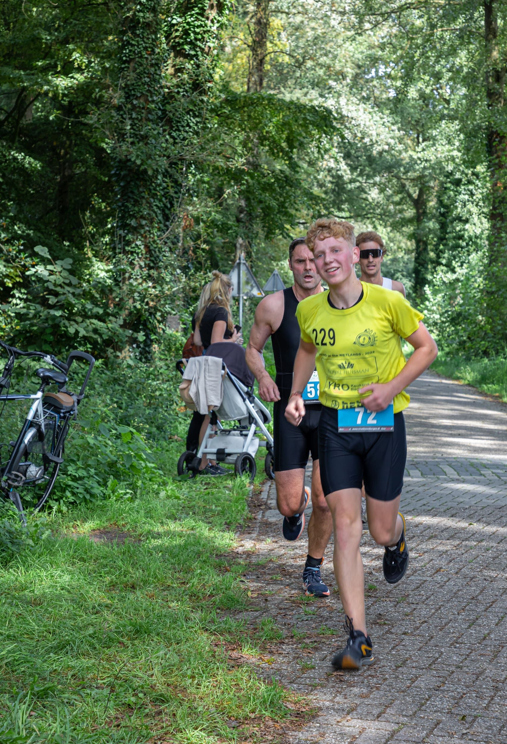 Een groep mensen rent over een onverharde weg in het bos.